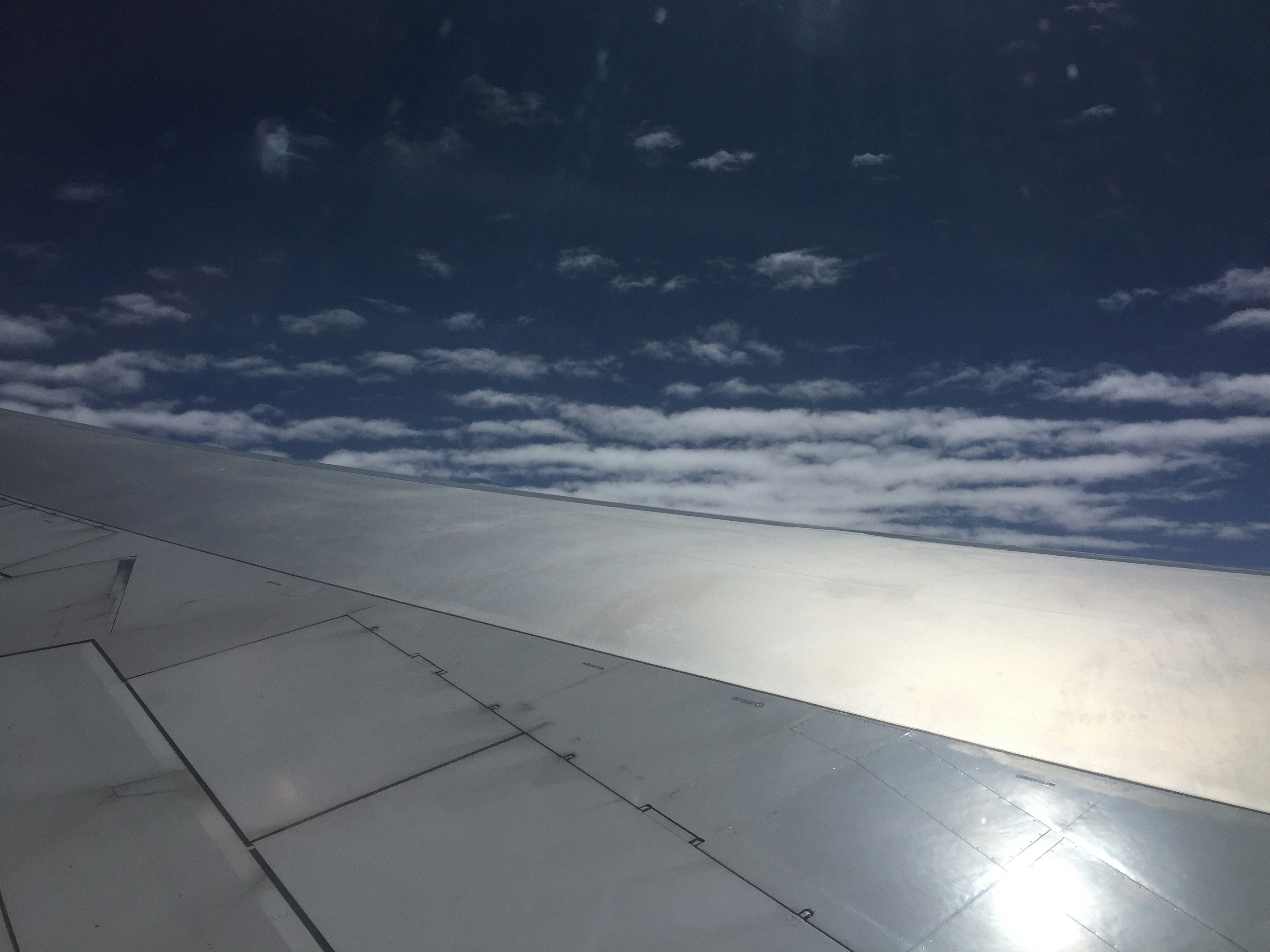 Blick auf den blauen Himmel und die Wolken von einem Flugzeugflügel