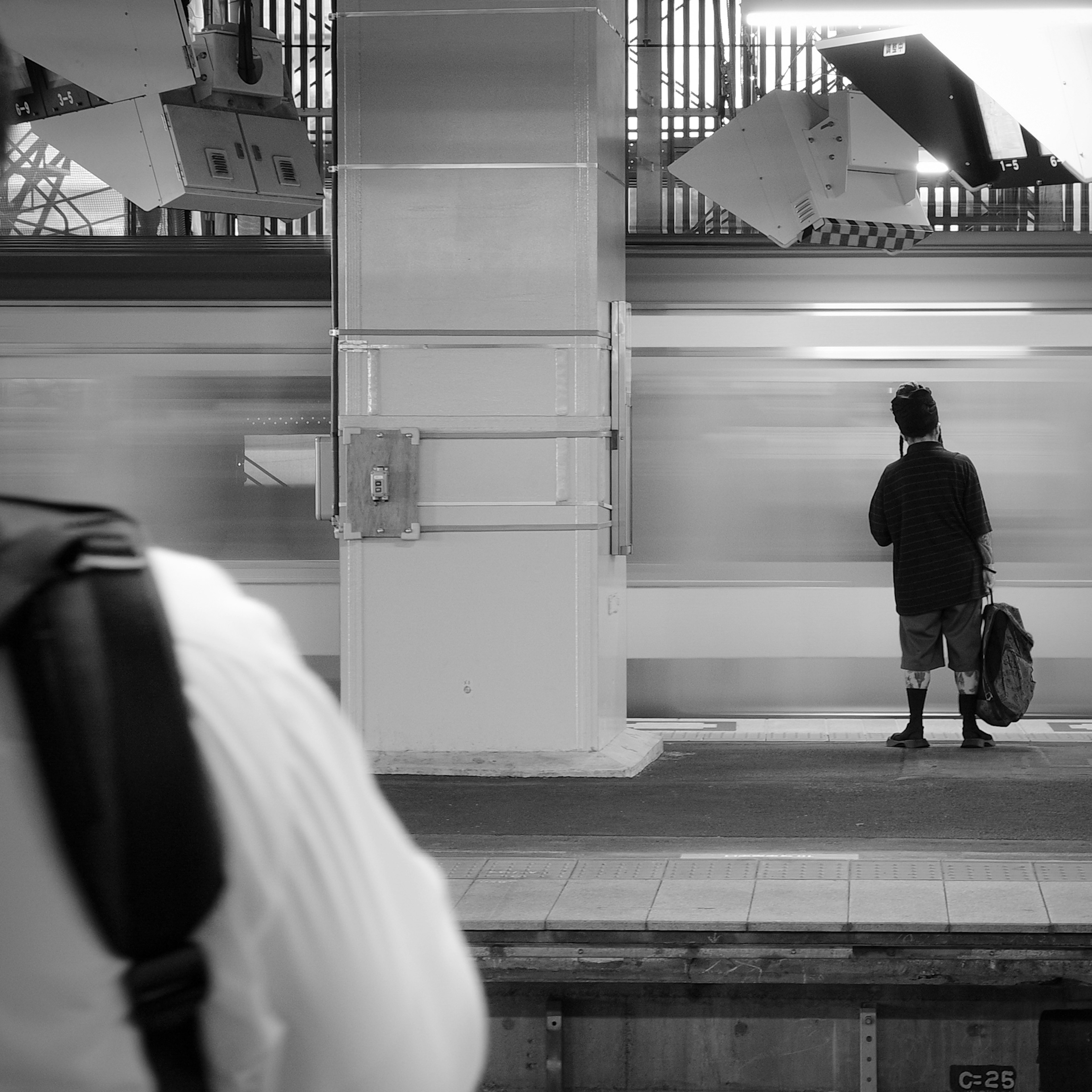 Ein Junge steht auf einem Bahnsteig mit einer Person in einem weißen Hemd im Vordergrund