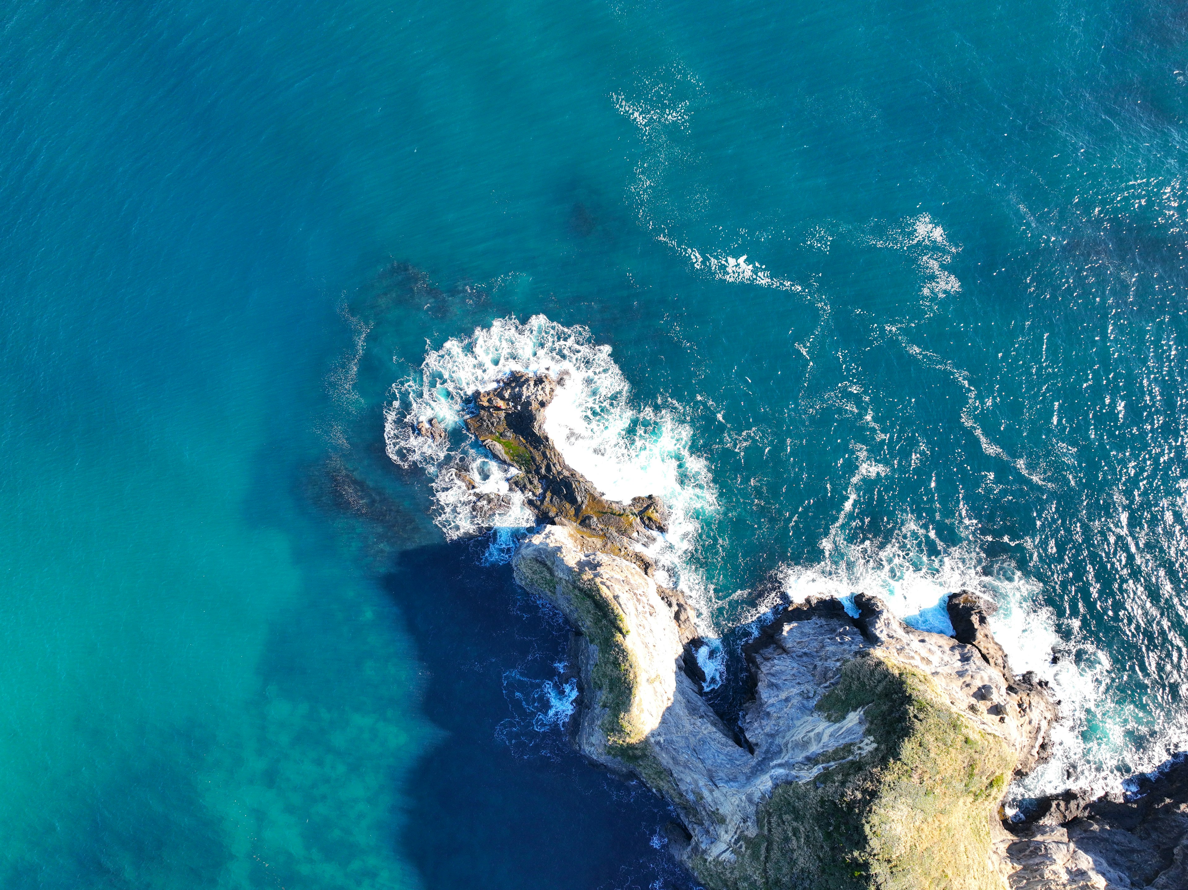 Aerial view of a coastline with blue ocean and rocky formations