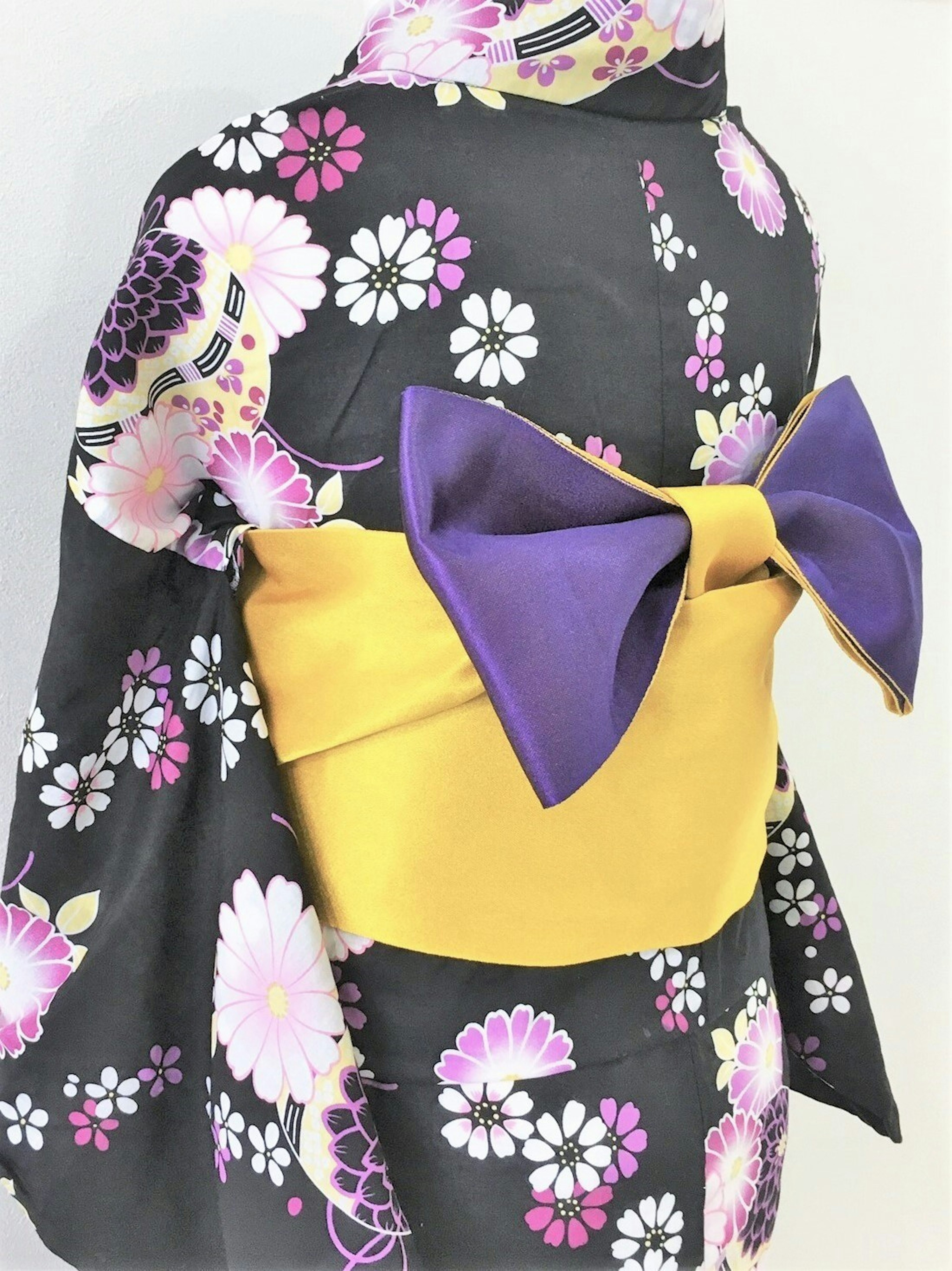 Kimono with floral patterns on black fabric and a purple bow