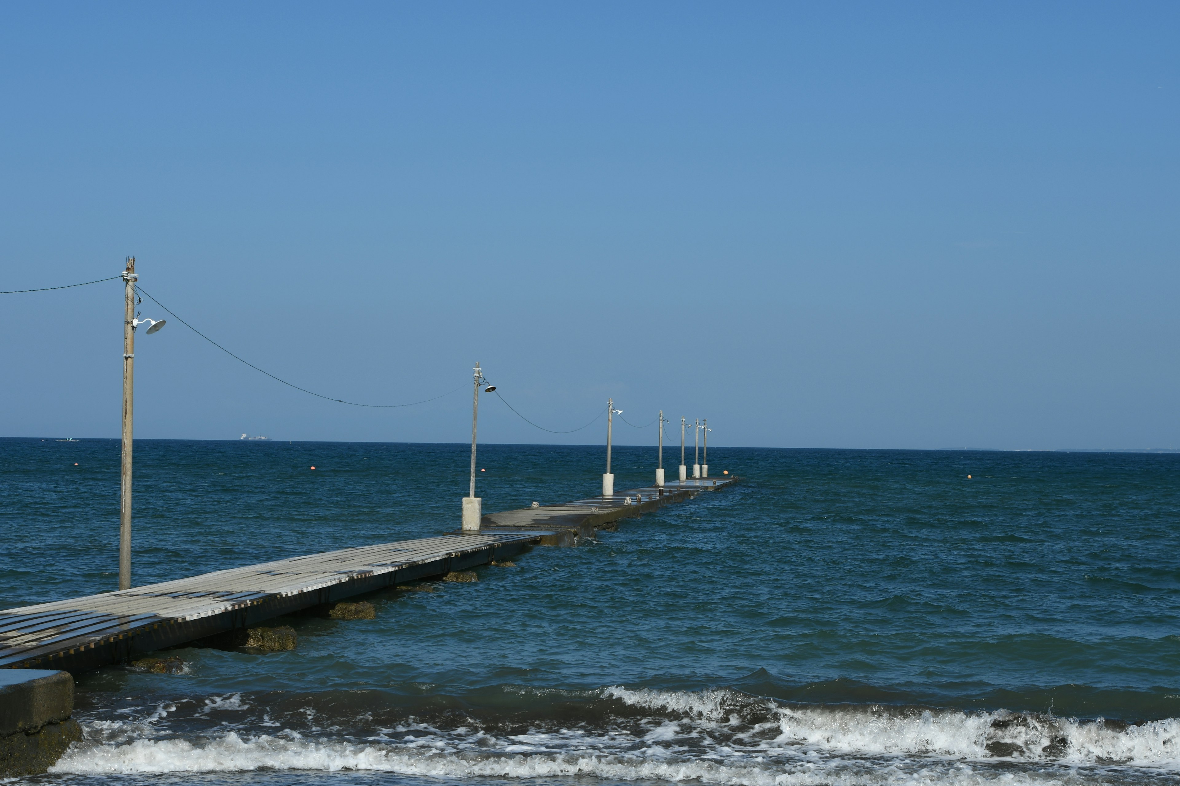 Szenische Ansicht eines Pier, der in das blaue Meer unter einem klaren Himmel ragt