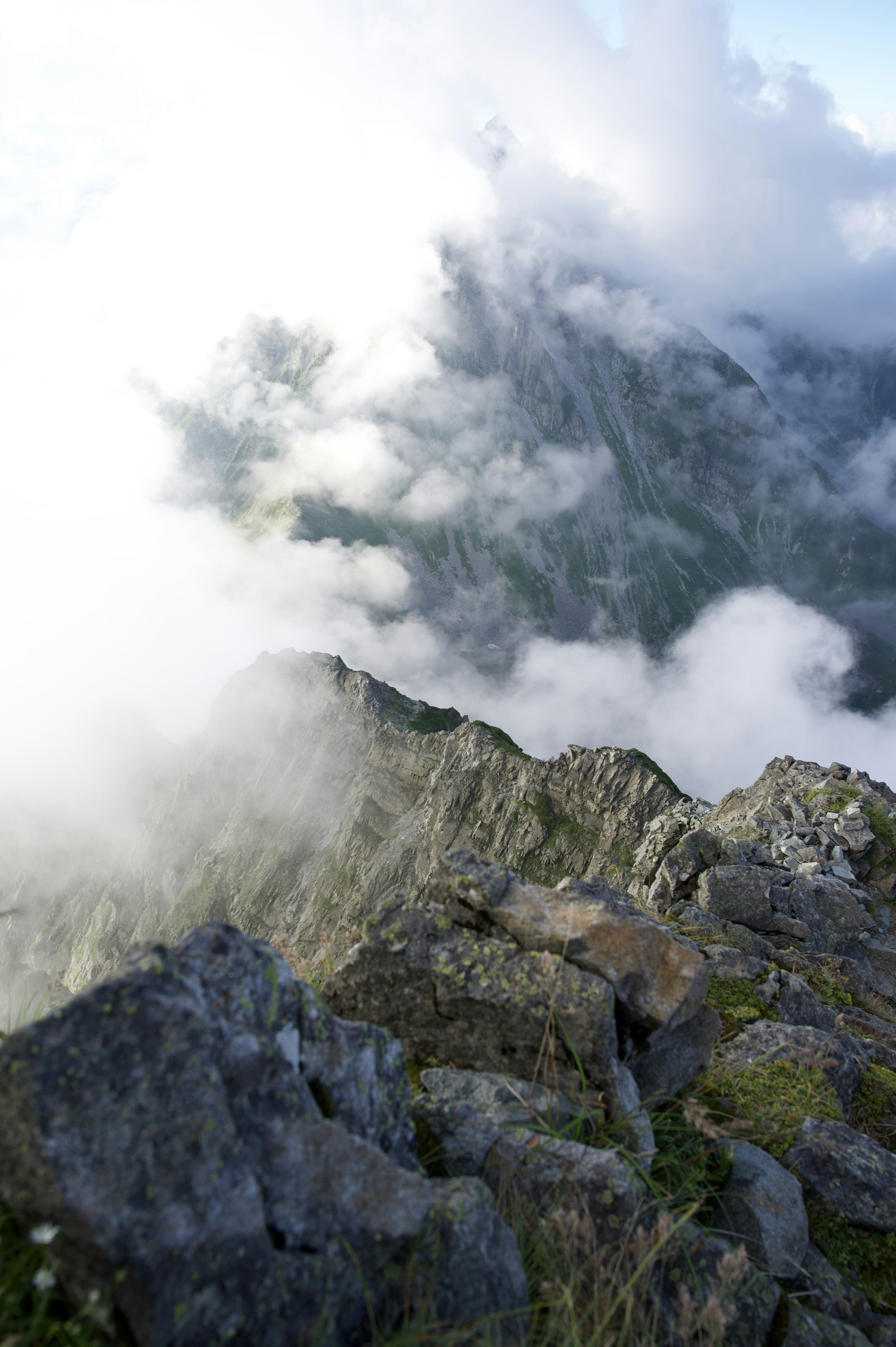 Paisaje montañoso envuelto en nubes con rocas y hierba visibles