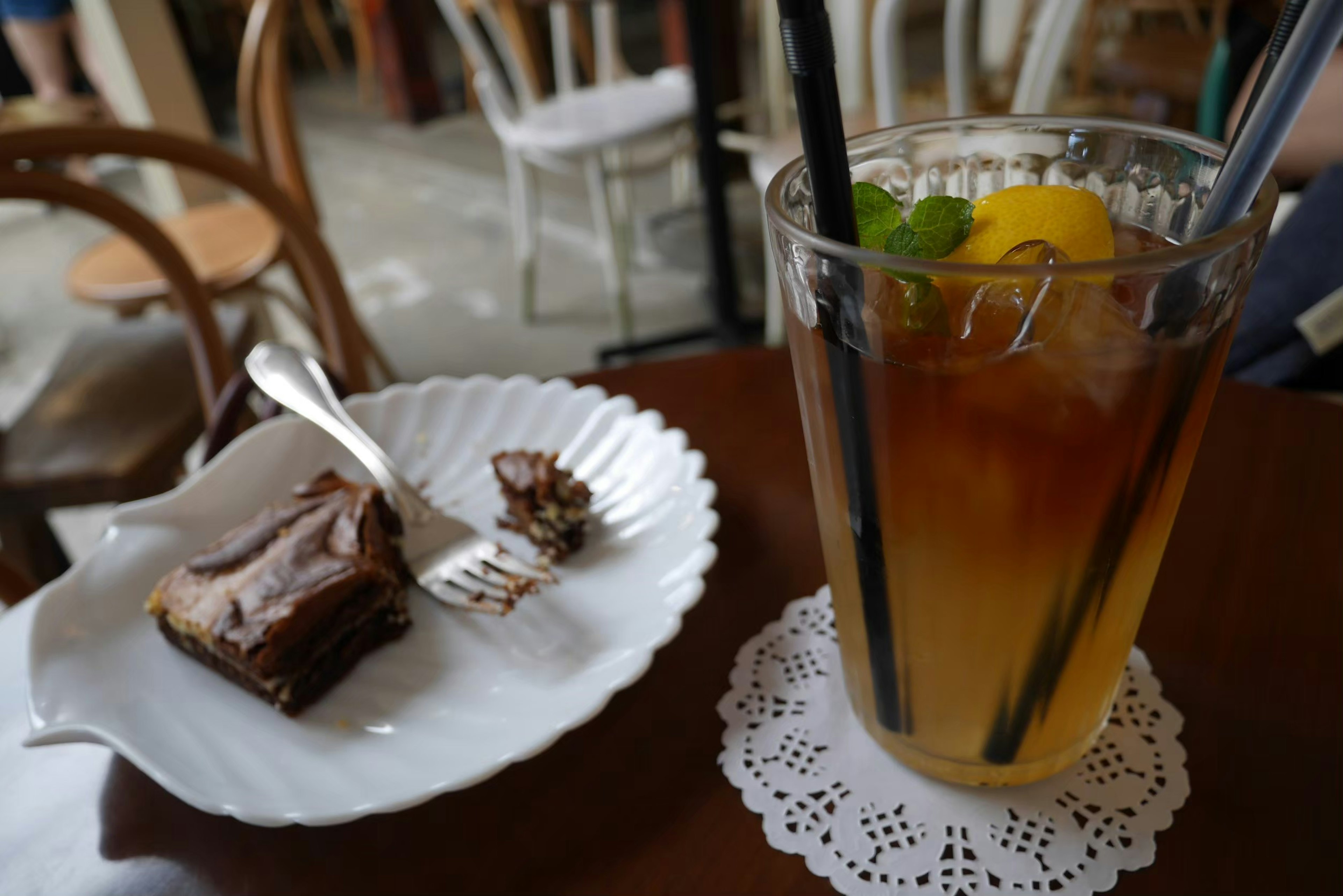 Un vaso de té helado con limón y menta al lado de un plato de pastel de chocolate