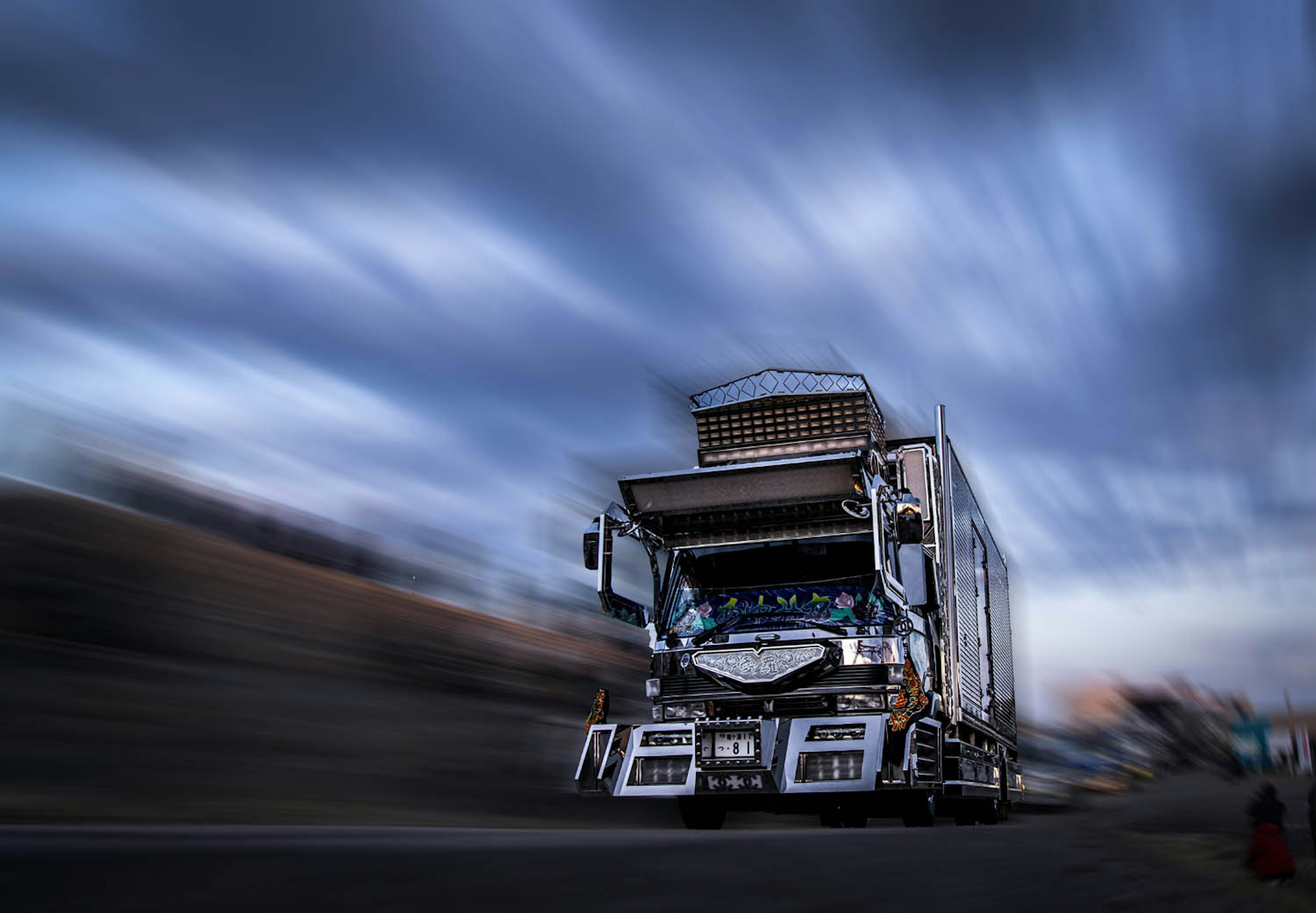 Image d'un camion en mouvement avec des nuages flous en arrière-plan évoquant la vitesse