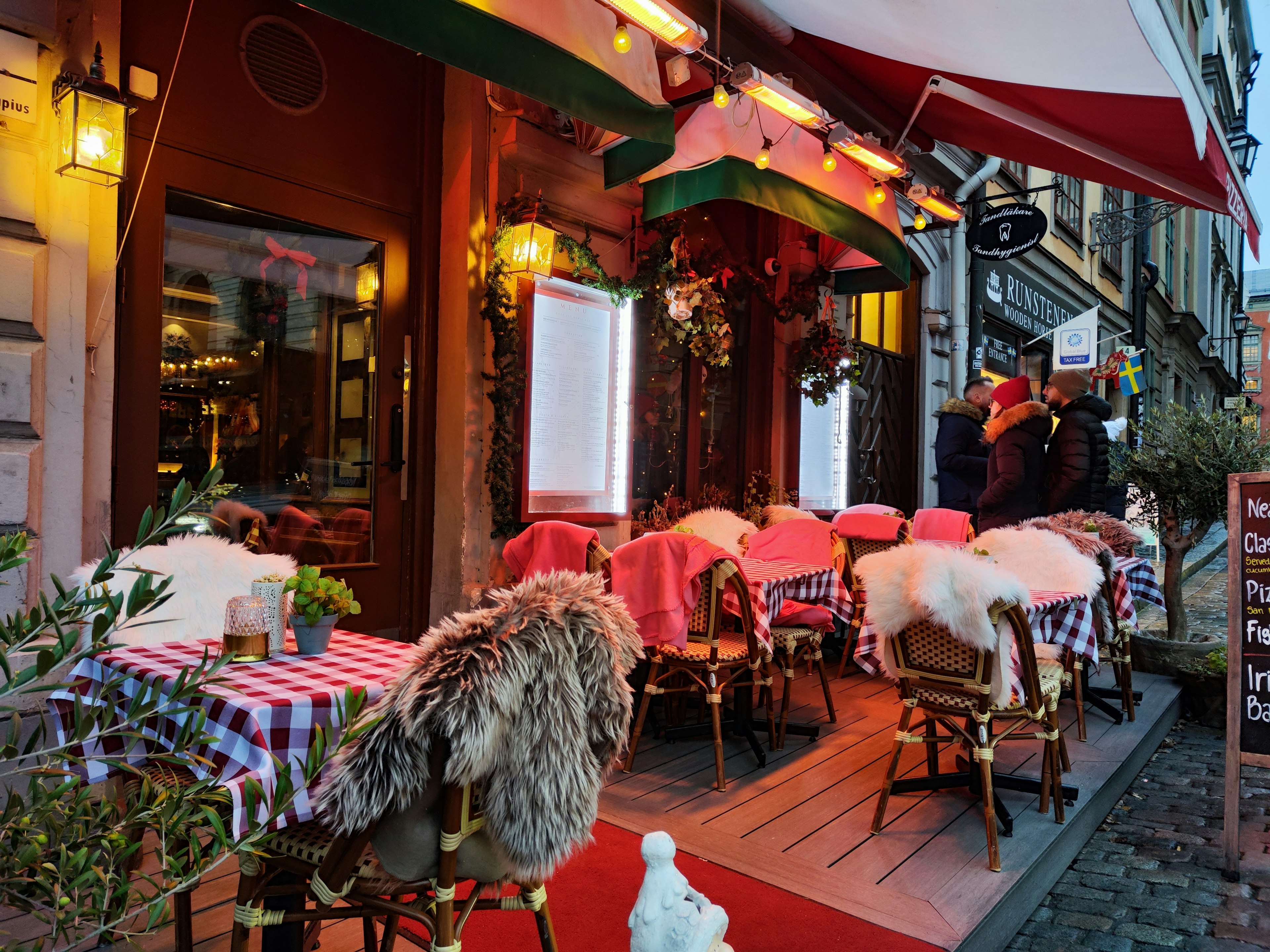 Gemütliche Café-Terrasse mit mit Pelz bedeckten Stühlen und karierten Tischdecken