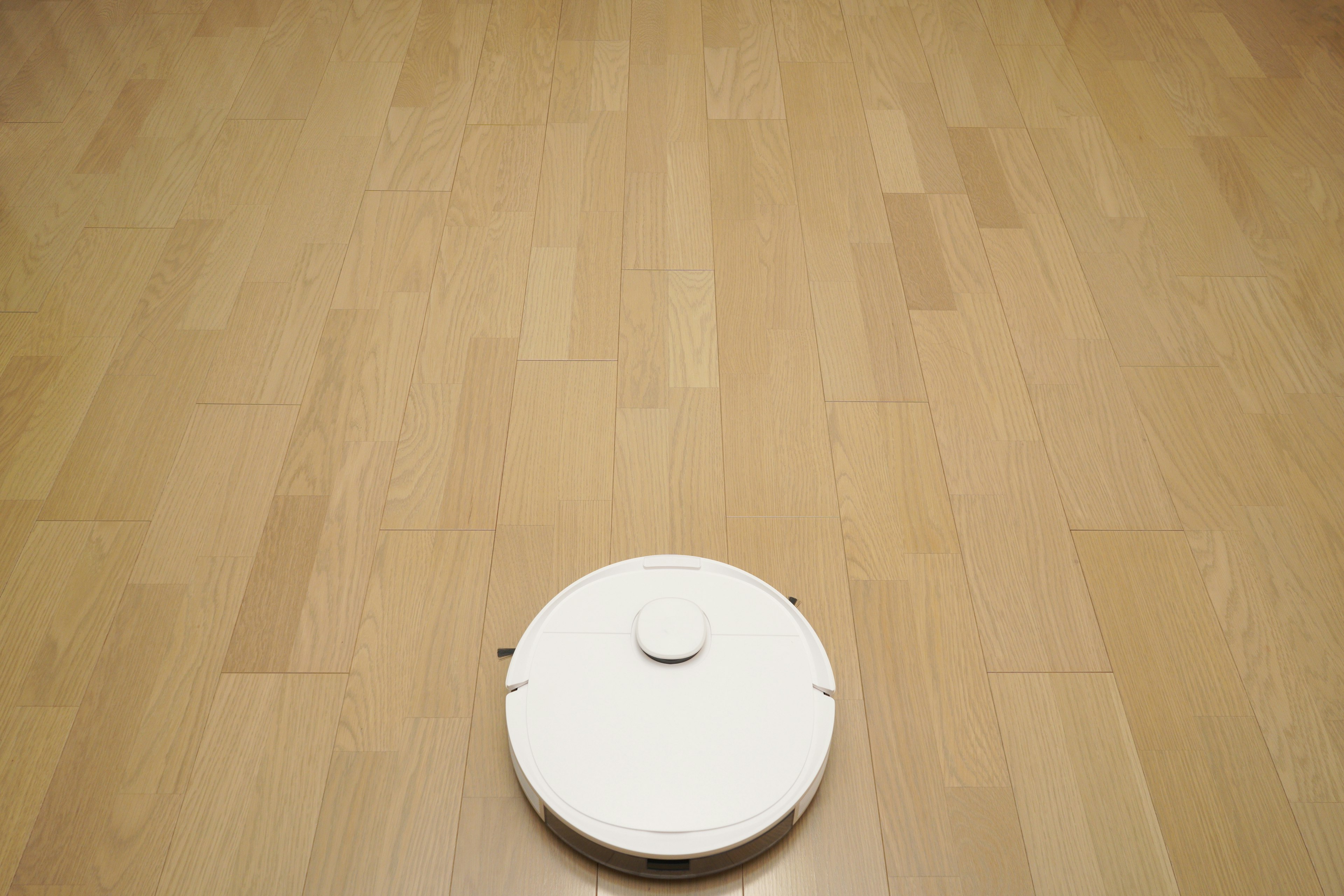 White robotic vacuum cleaner on wooden floor