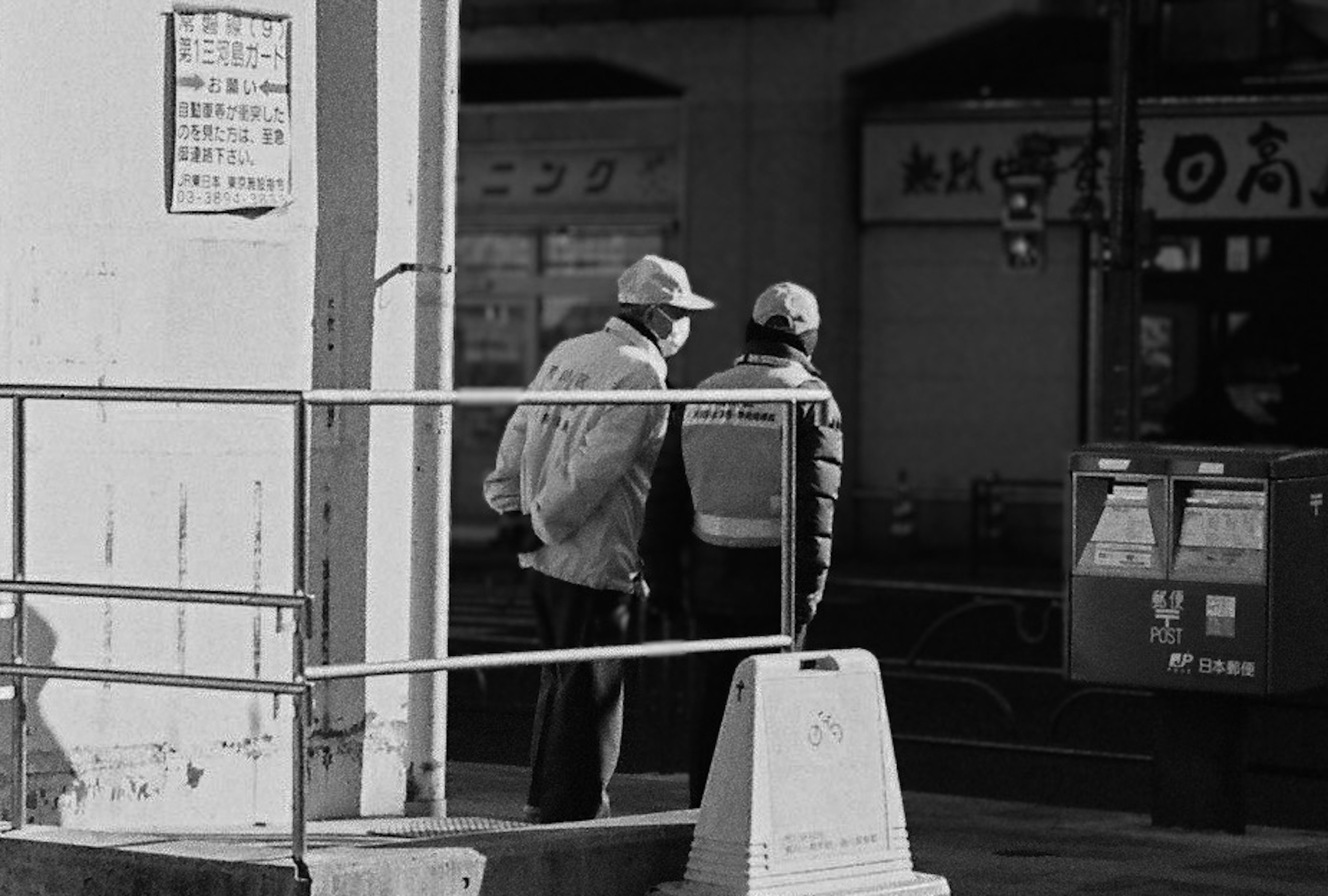 Two men talking at a street corner in black and white