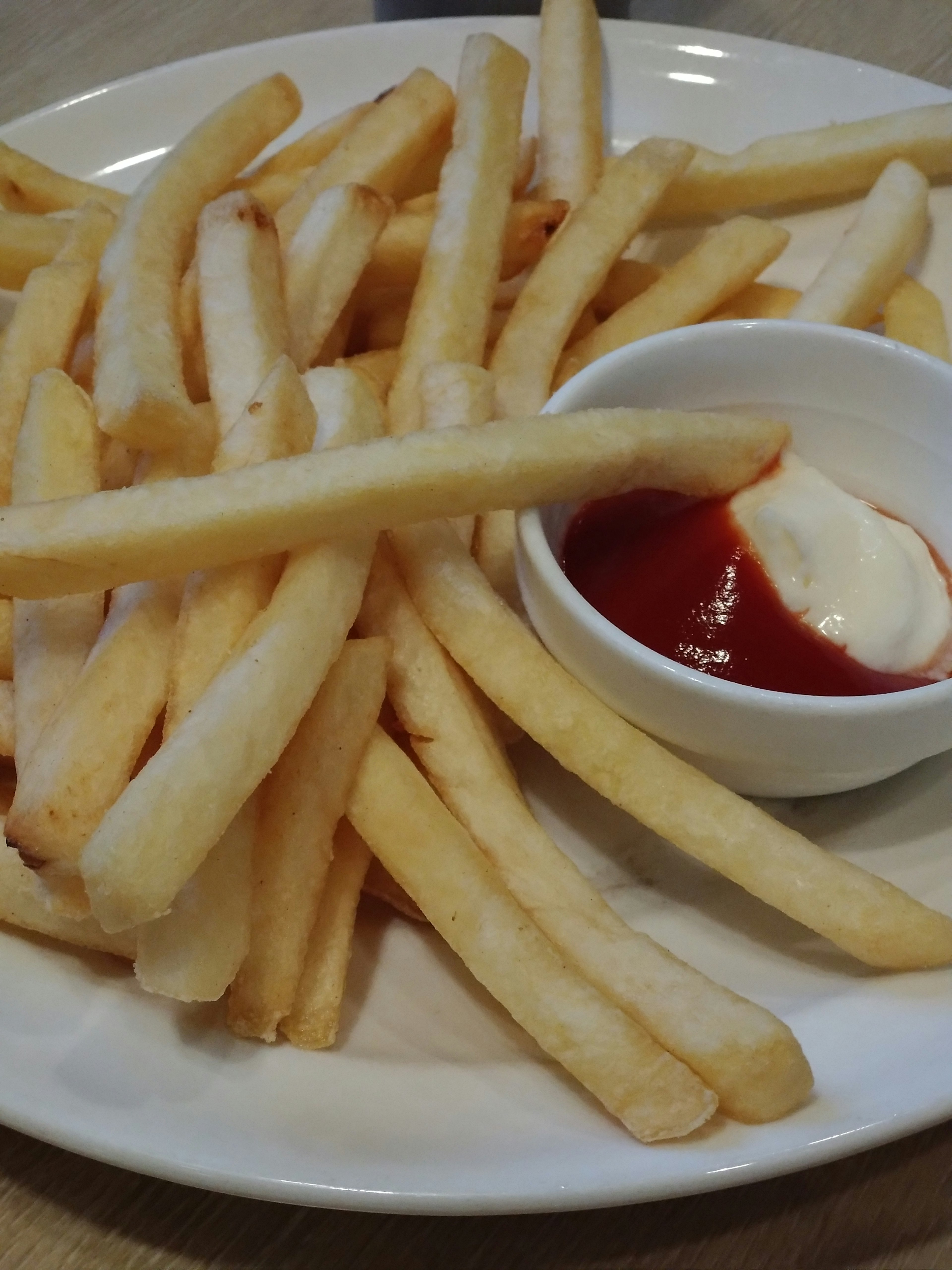 Plato de papas fritas doradas con ketchup y mayonesa