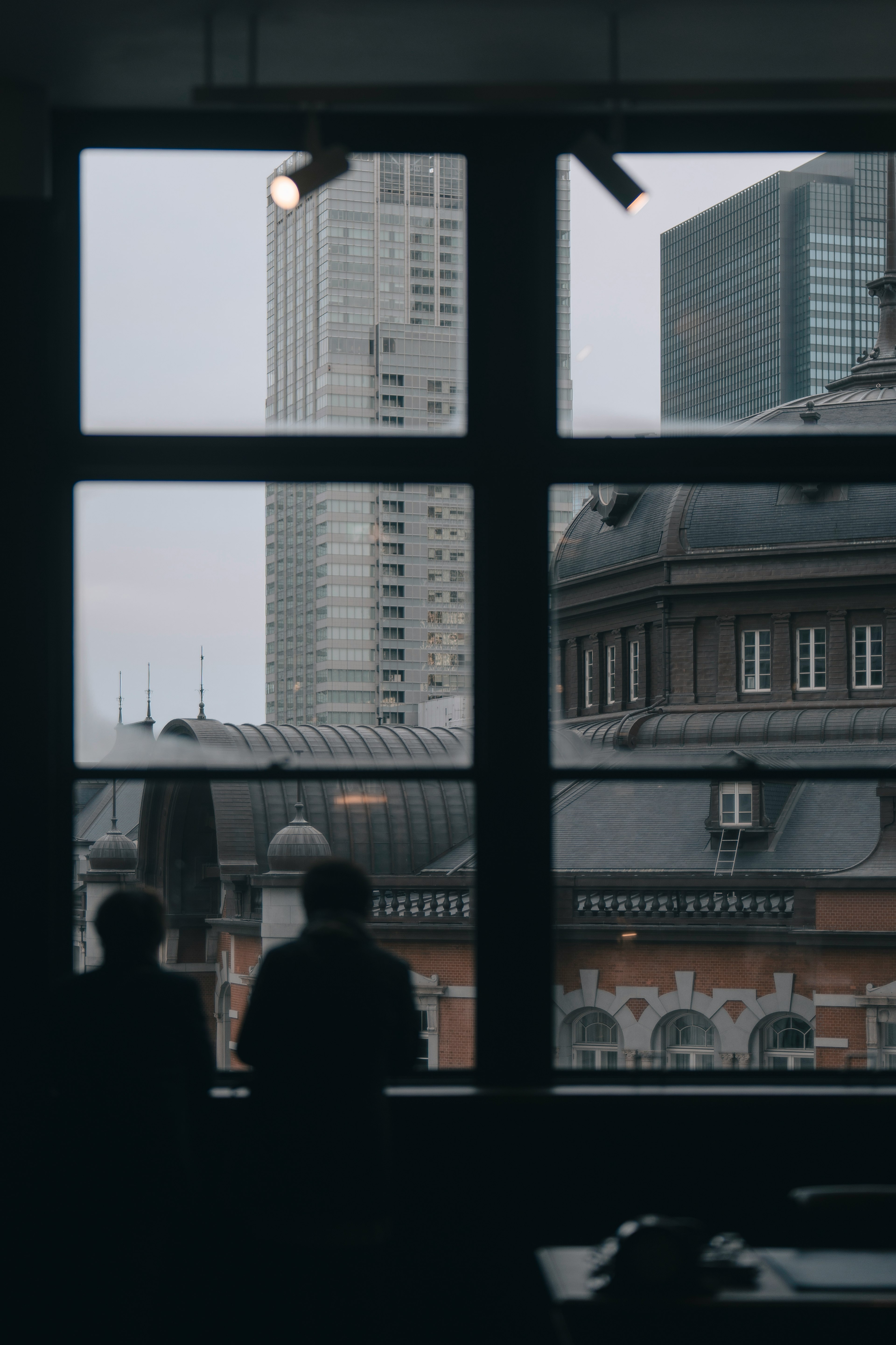 Two people looking out the window with skyscrapers and historical buildings visible