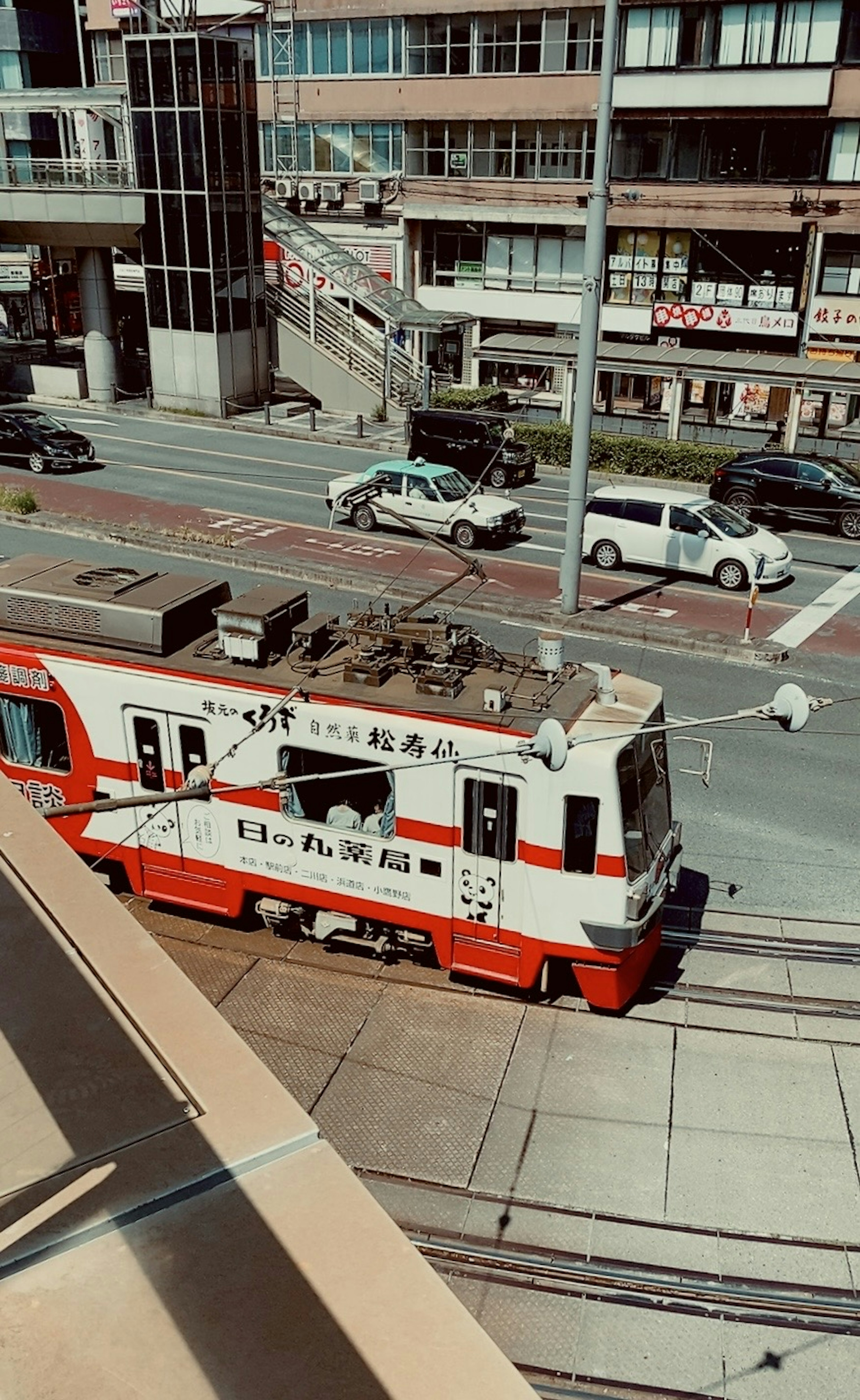 A red and white tram running through an urban street