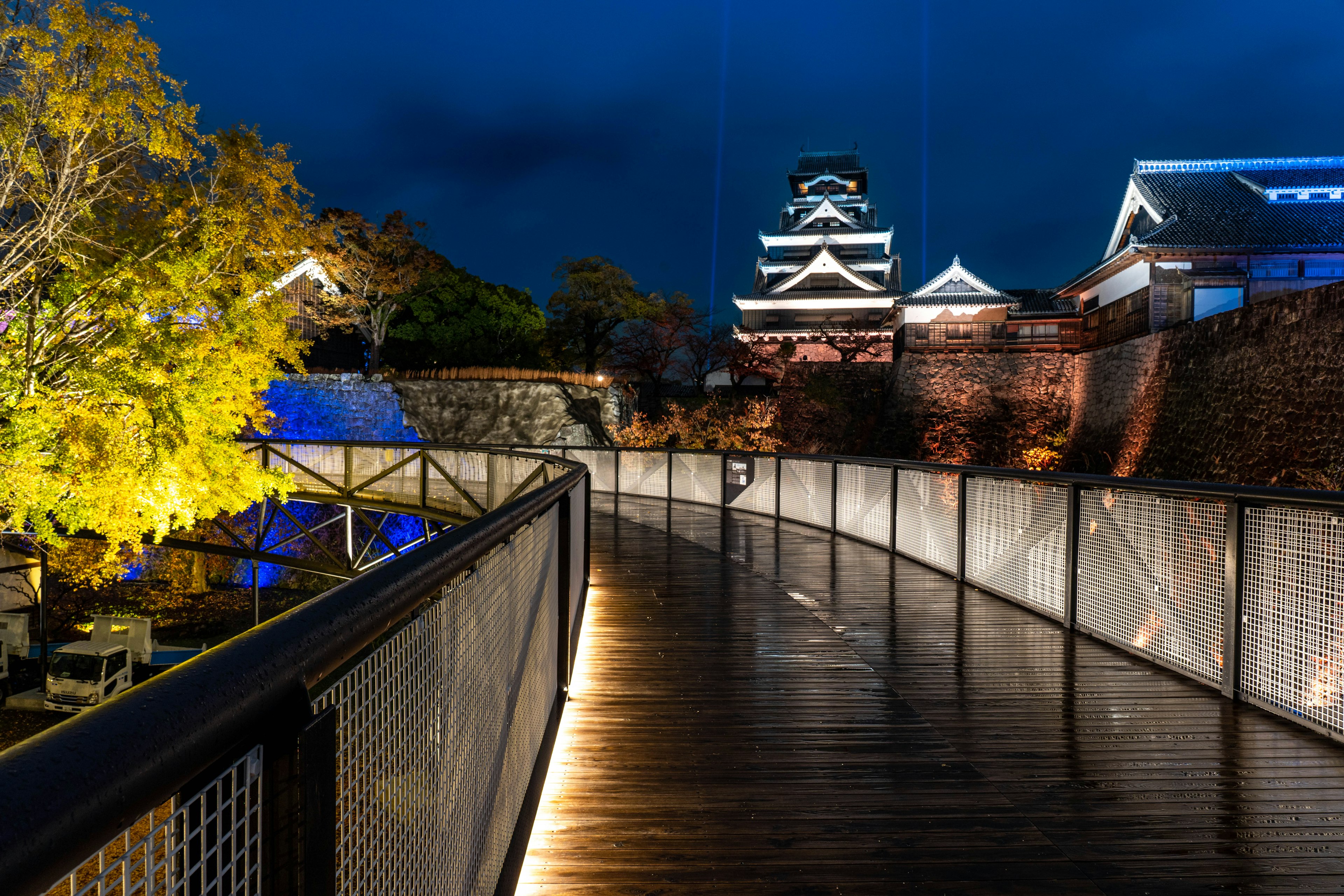 Beautiful view of Kumamoto Castle at night with illuminated wooden walkway