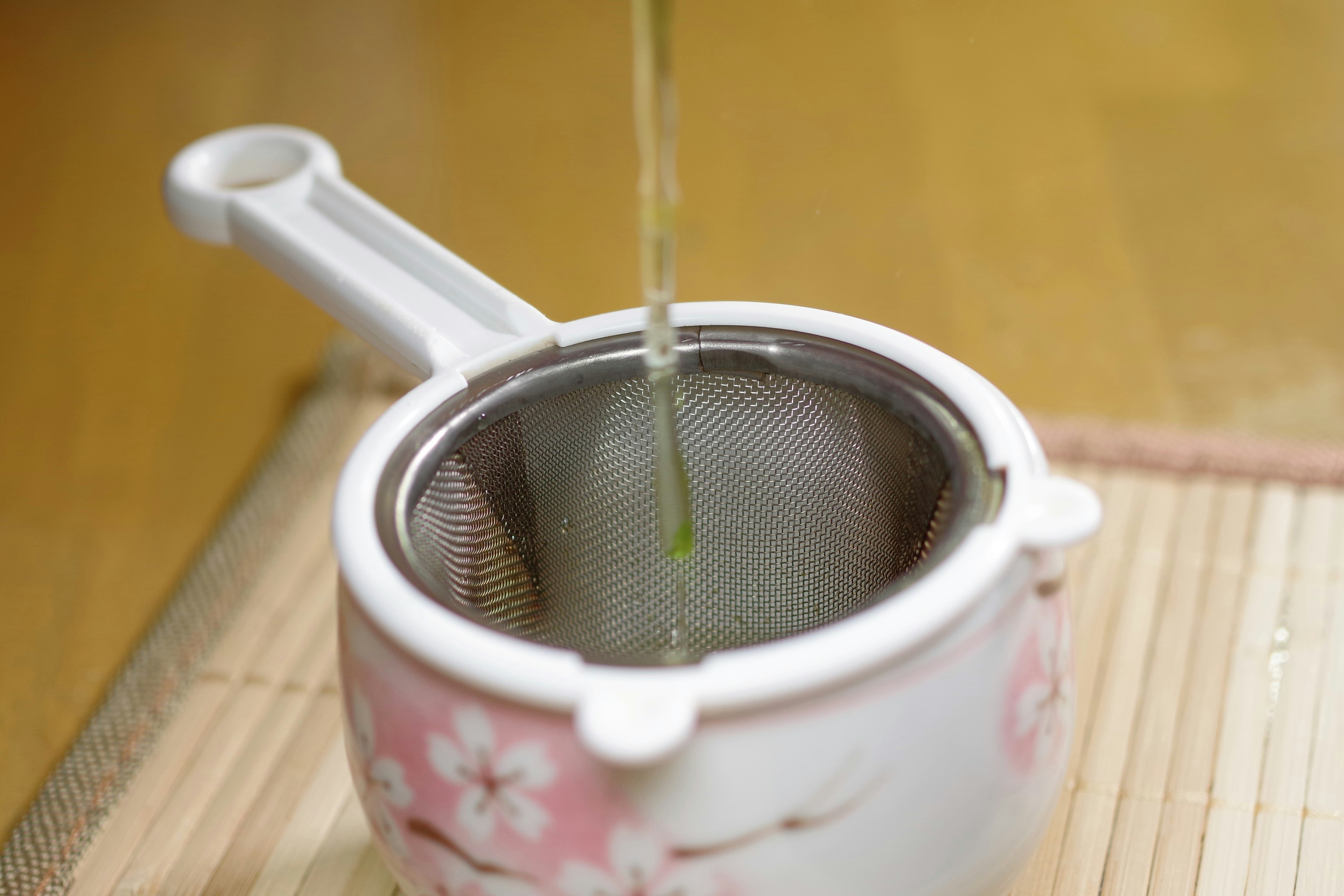 Tea being poured into a floral tea strainer