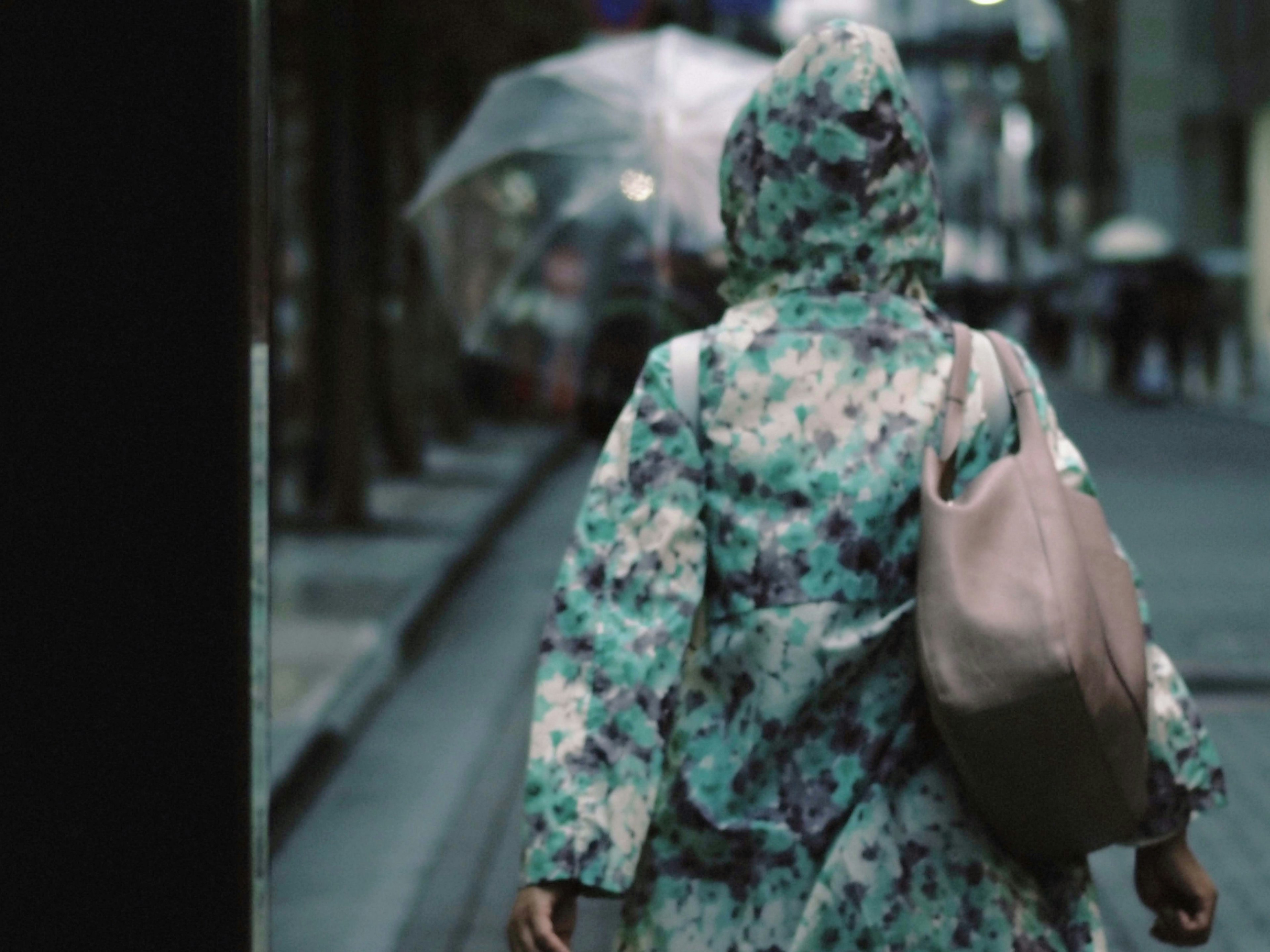 一个穿着花卉外套的女人在雨天的街道上行走