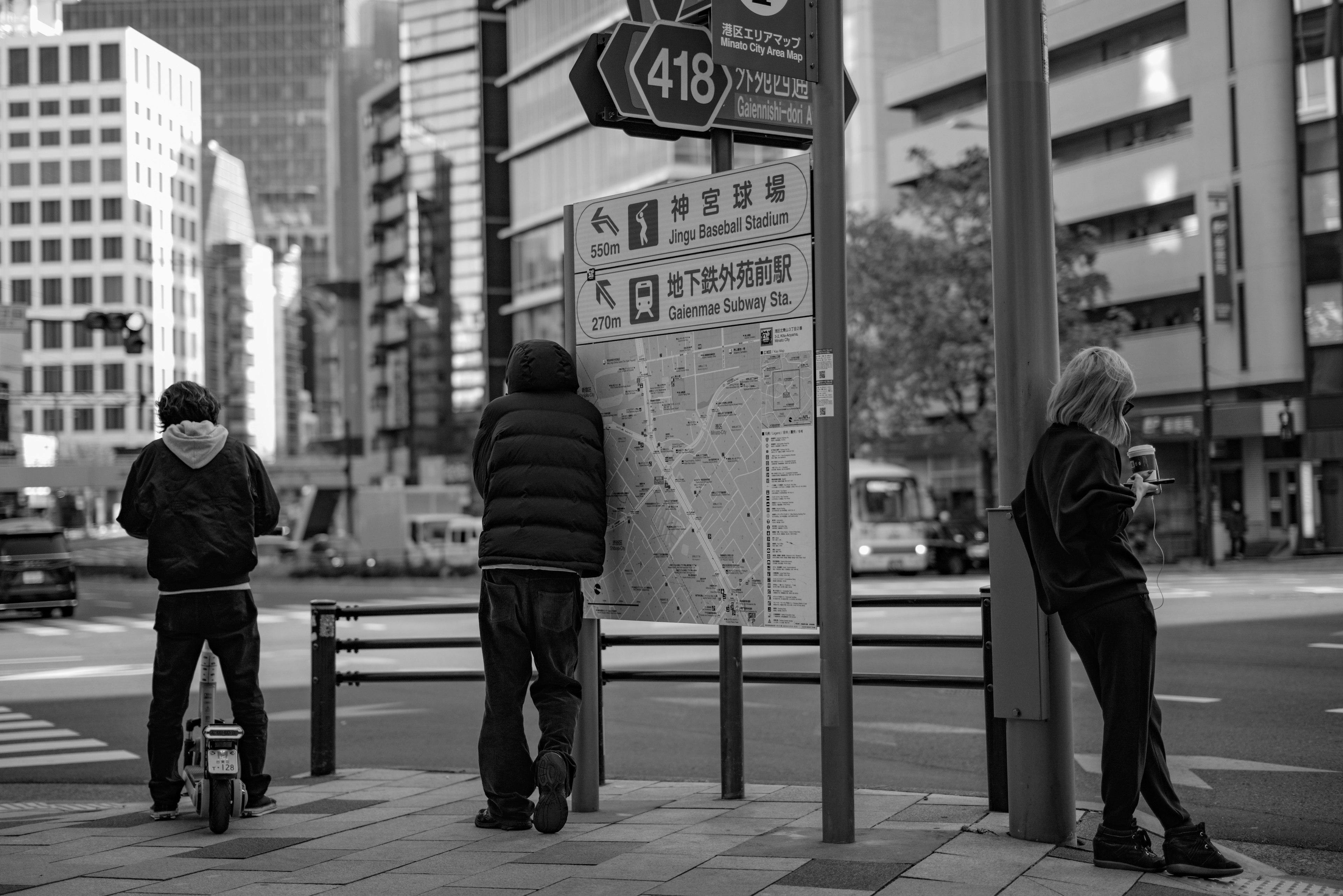 Fotografia in bianco e nero di tre persone che aspettano a un incrocio urbano