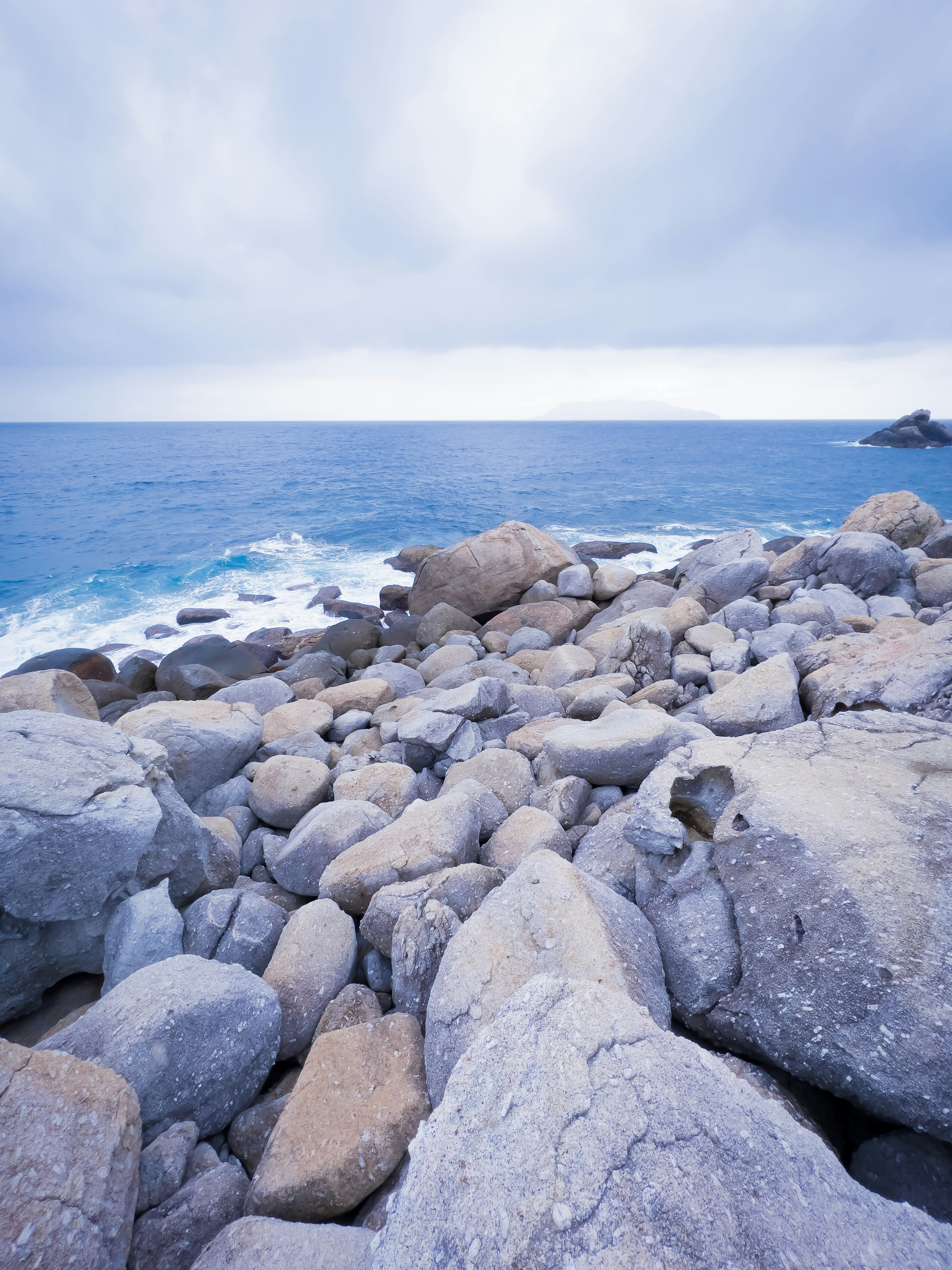 Rocky shoreline with blue ocean and cloudy sky