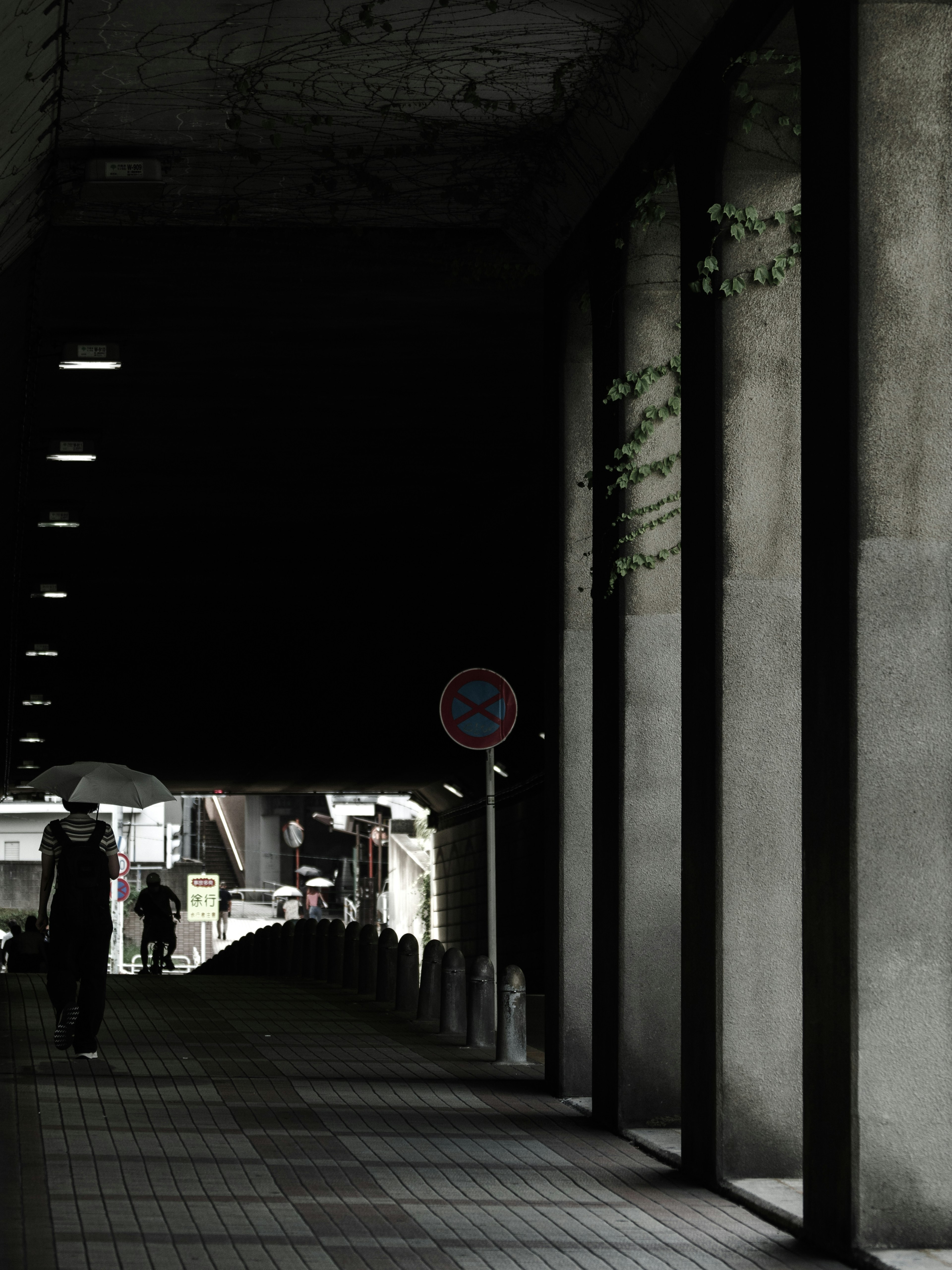 A dark passageway with a person standing and streetlights illuminating the scene