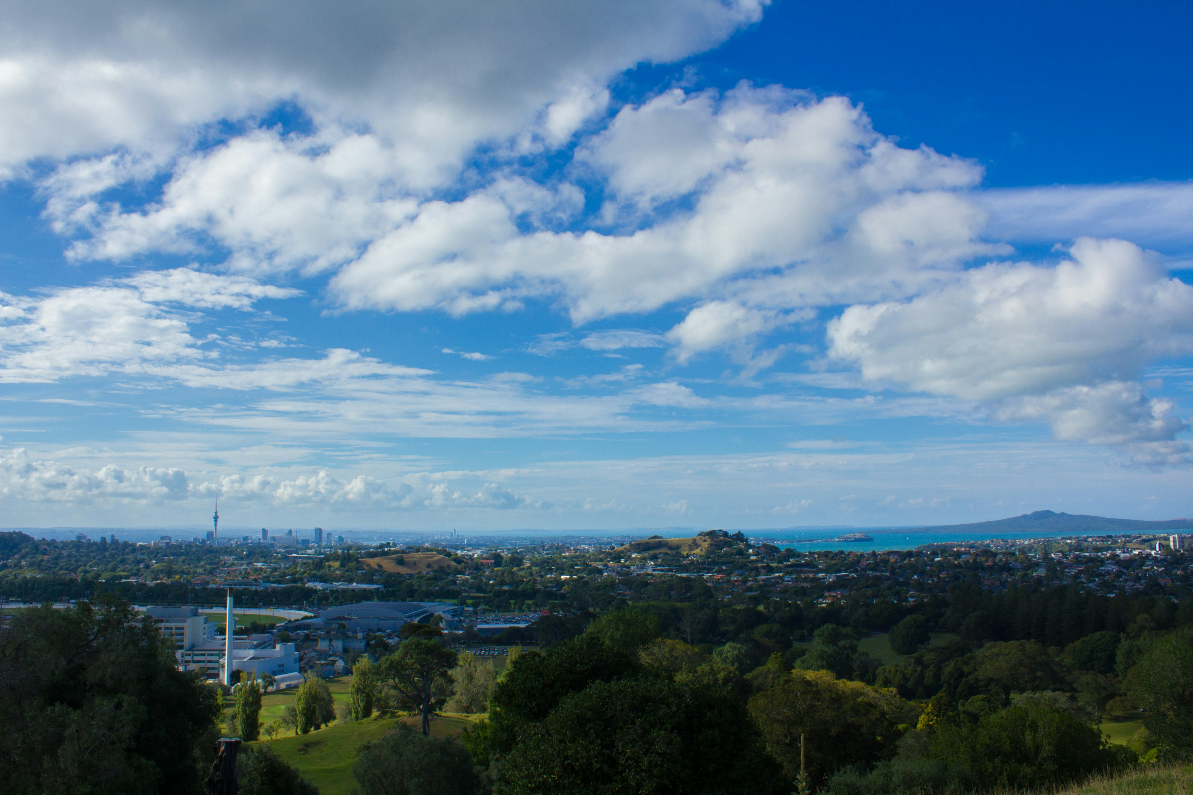 Panoramablick auf Neuseeland mit blauem Himmel Wolken grünen Hügeln und einer entfernten Stadtsilhouette