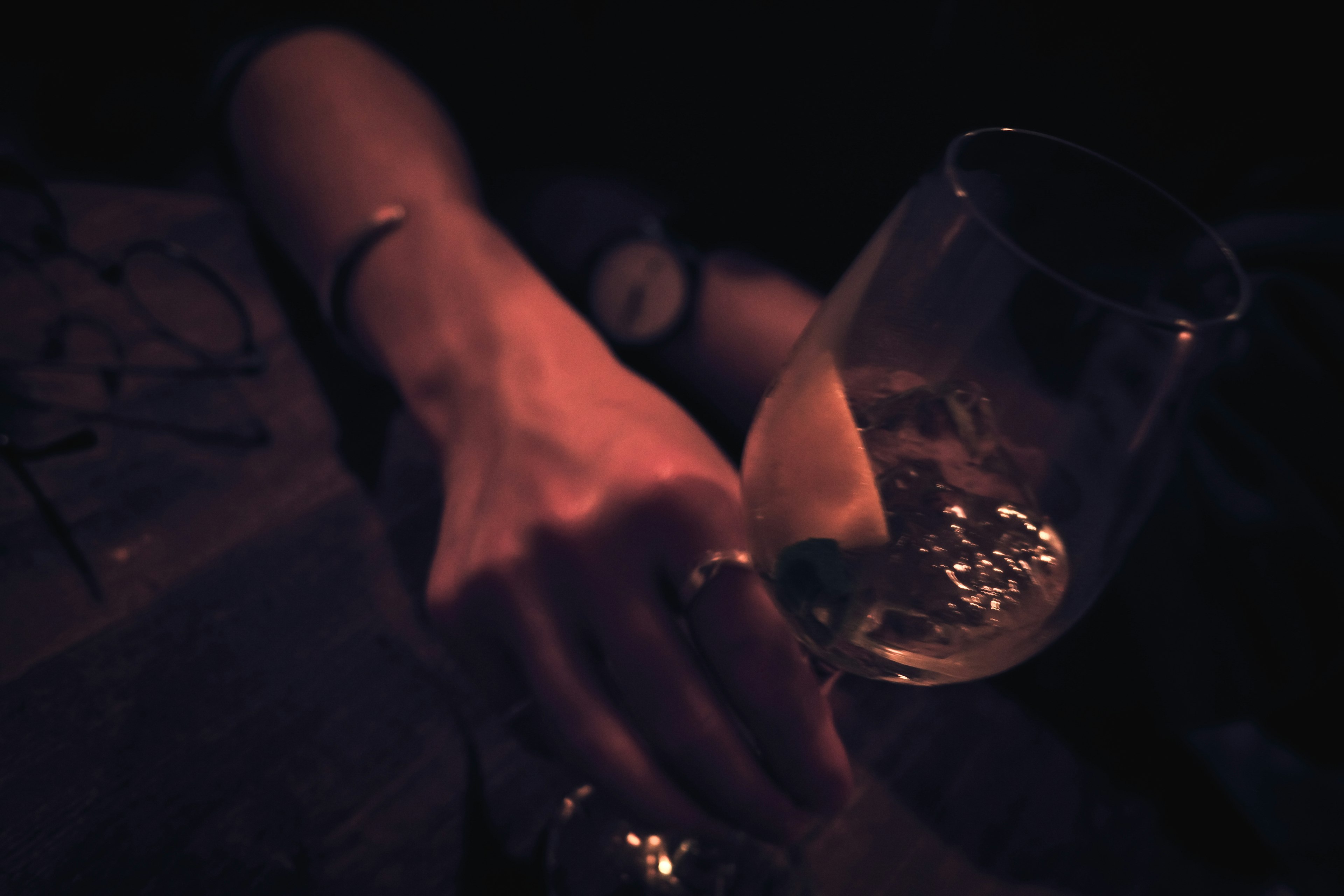 Hand holding a cocktail glass with a slice of lemon in a dimly lit setting