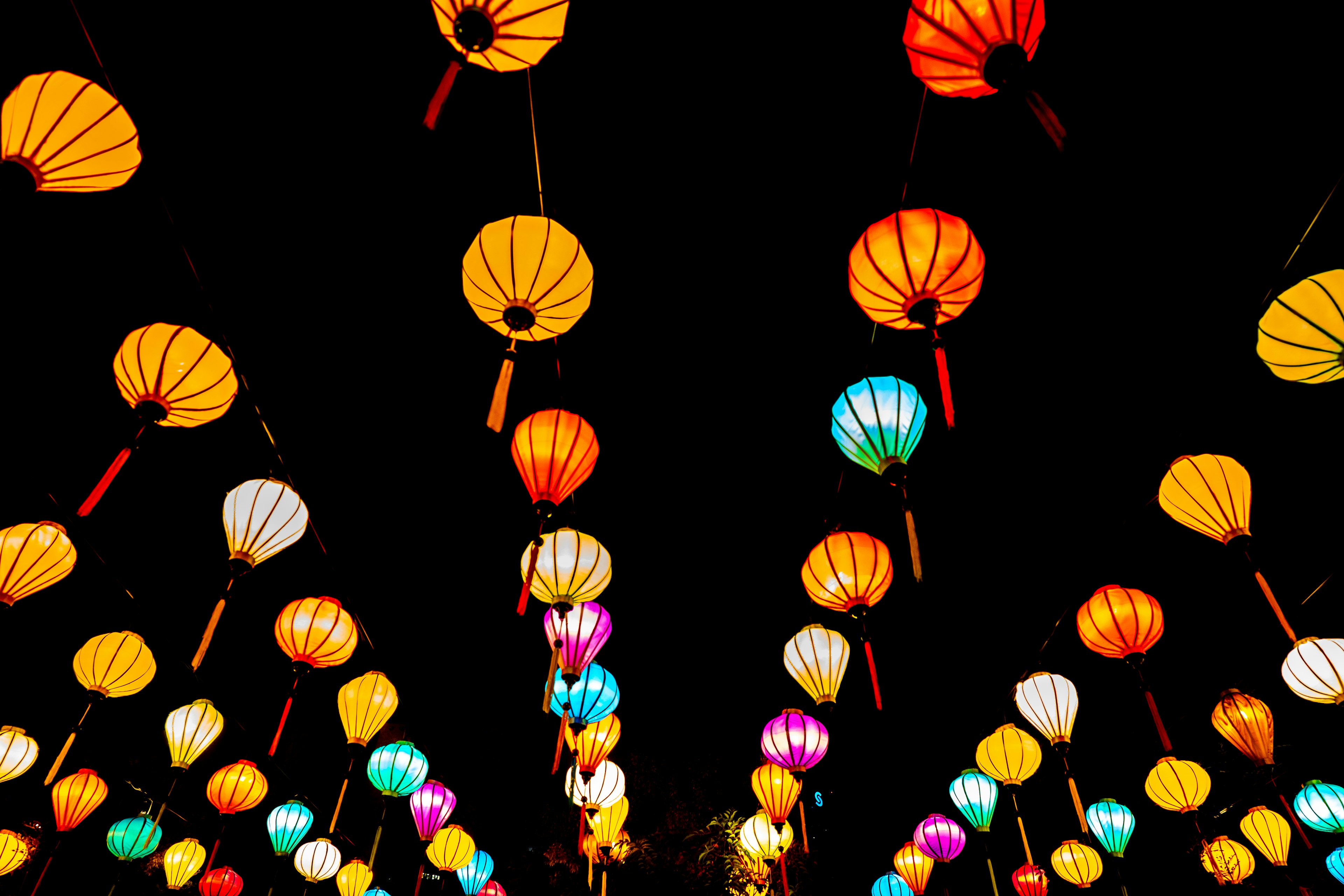 Colorful lanterns hanging against a dark sky creating a vibrant atmosphere