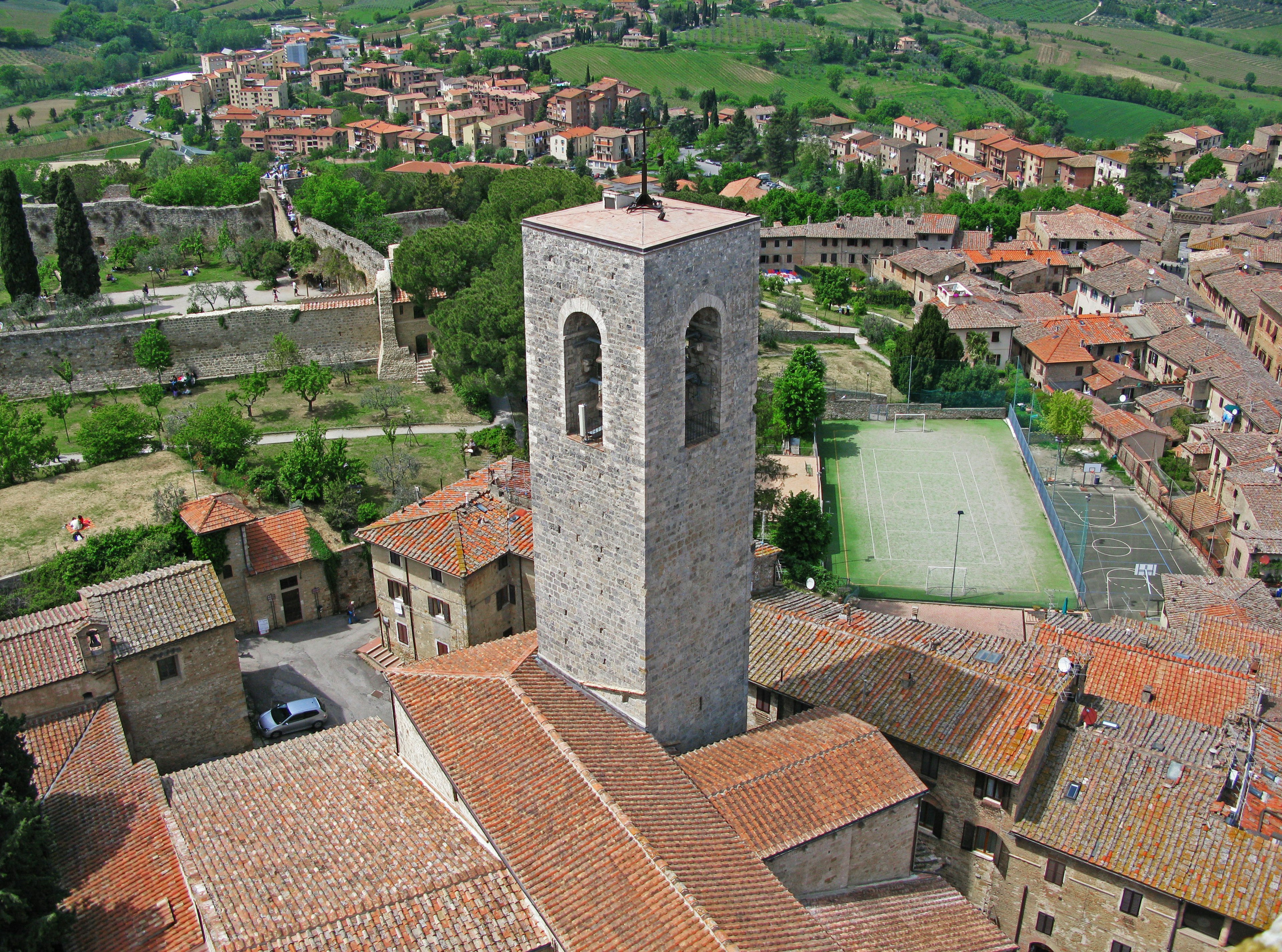 A scenic view of a Tuscan village featuring a stone tower and terracotta rooftops