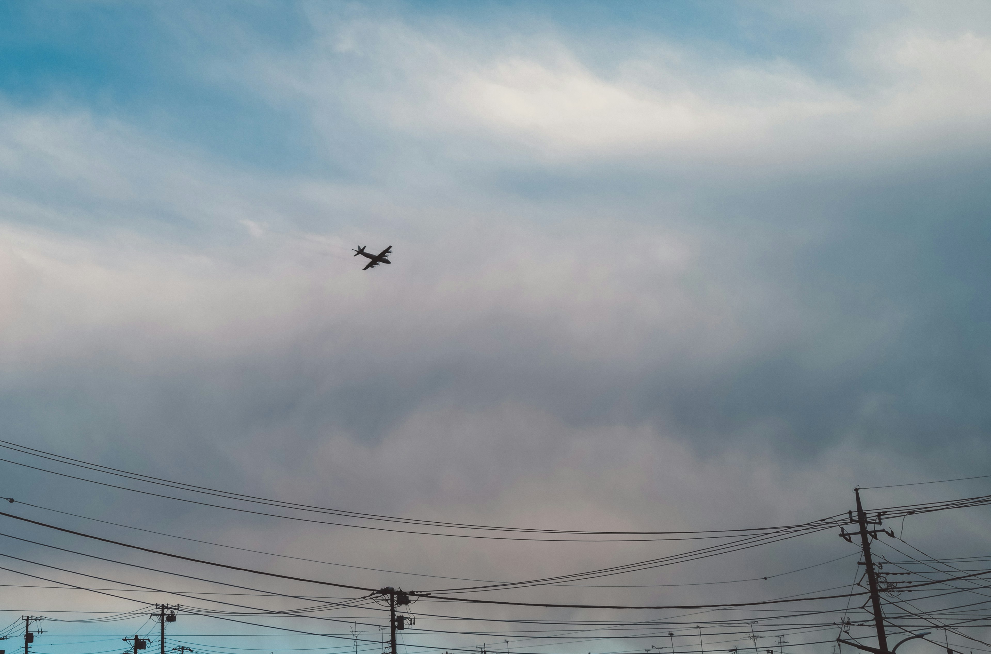 An airplane flying above clouds and power lines