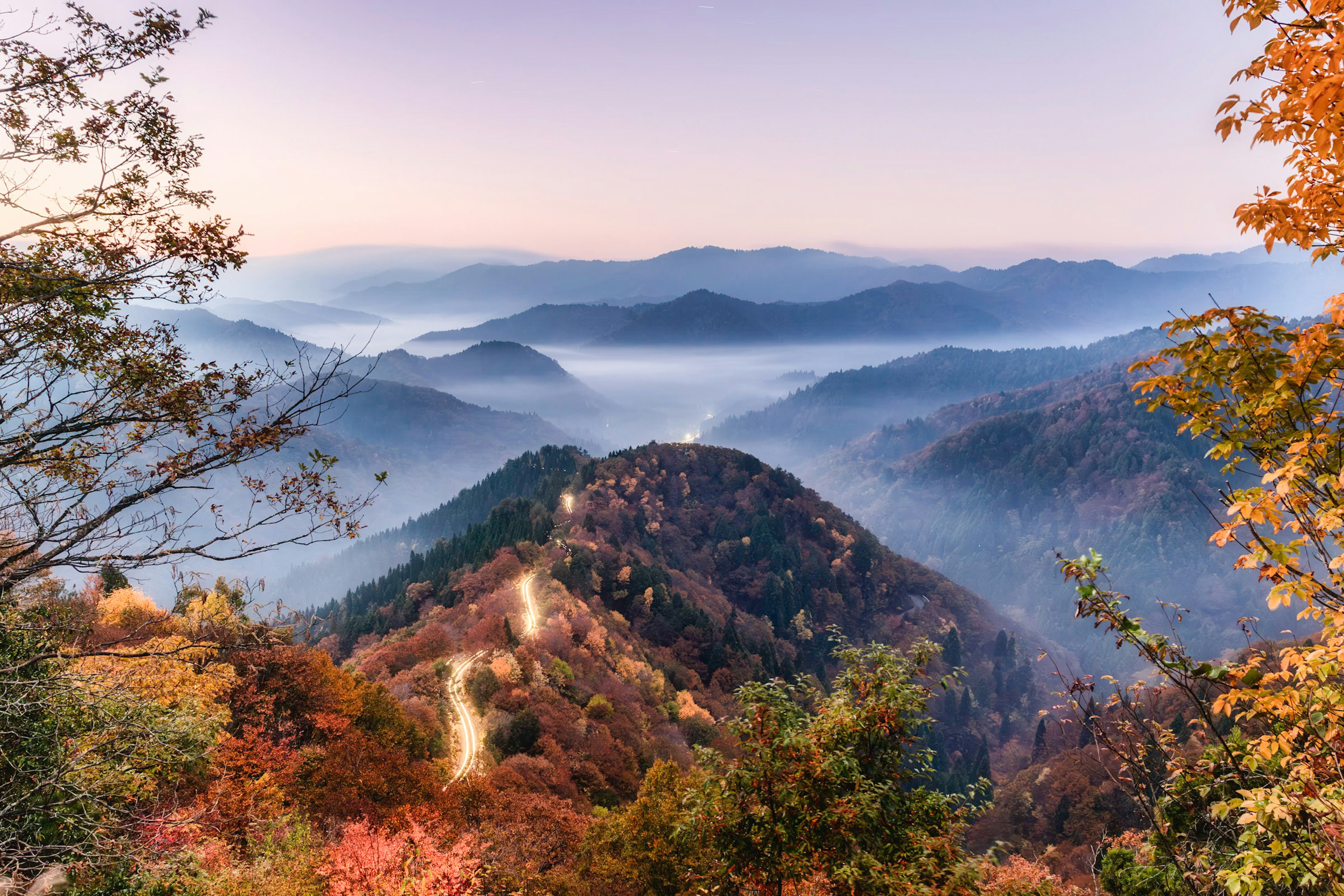 A beautiful landscape of mountains adorned with autumn colors and valleys shrouded in mist