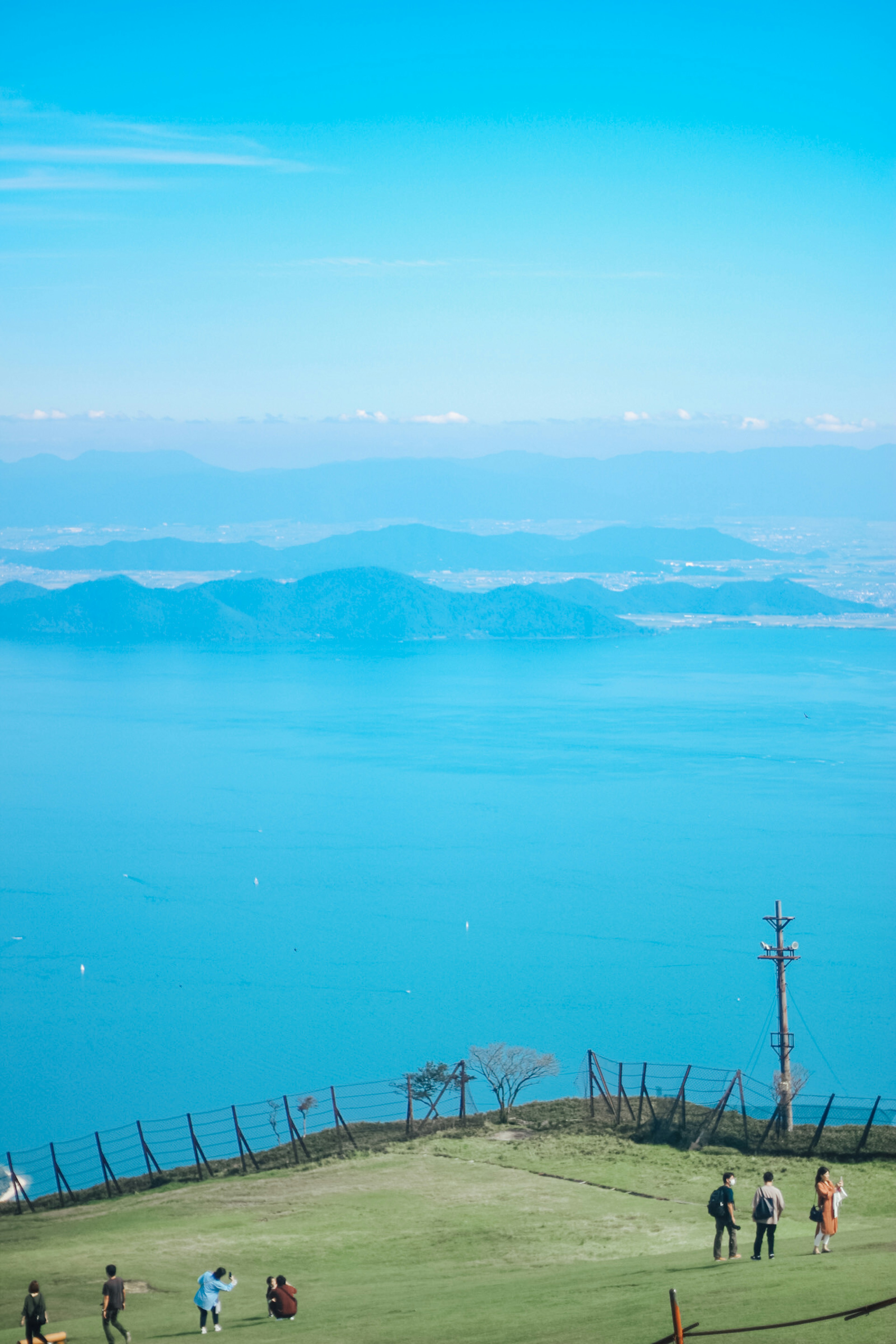 寬廣的草地上，人們在欣賞藍色海洋和背景中的島嶼