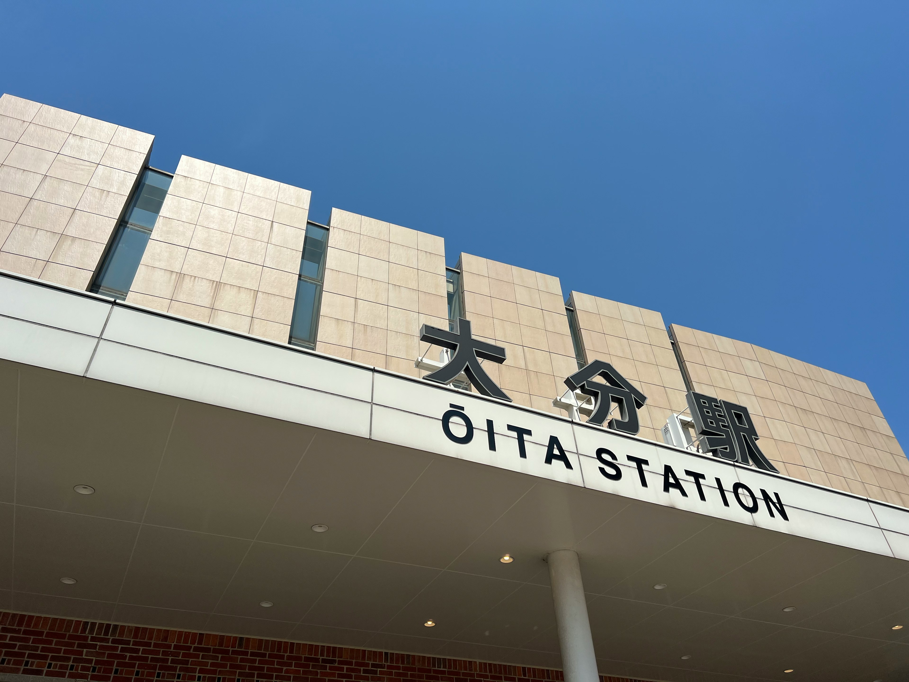 Oita Station sign visible under blue sky