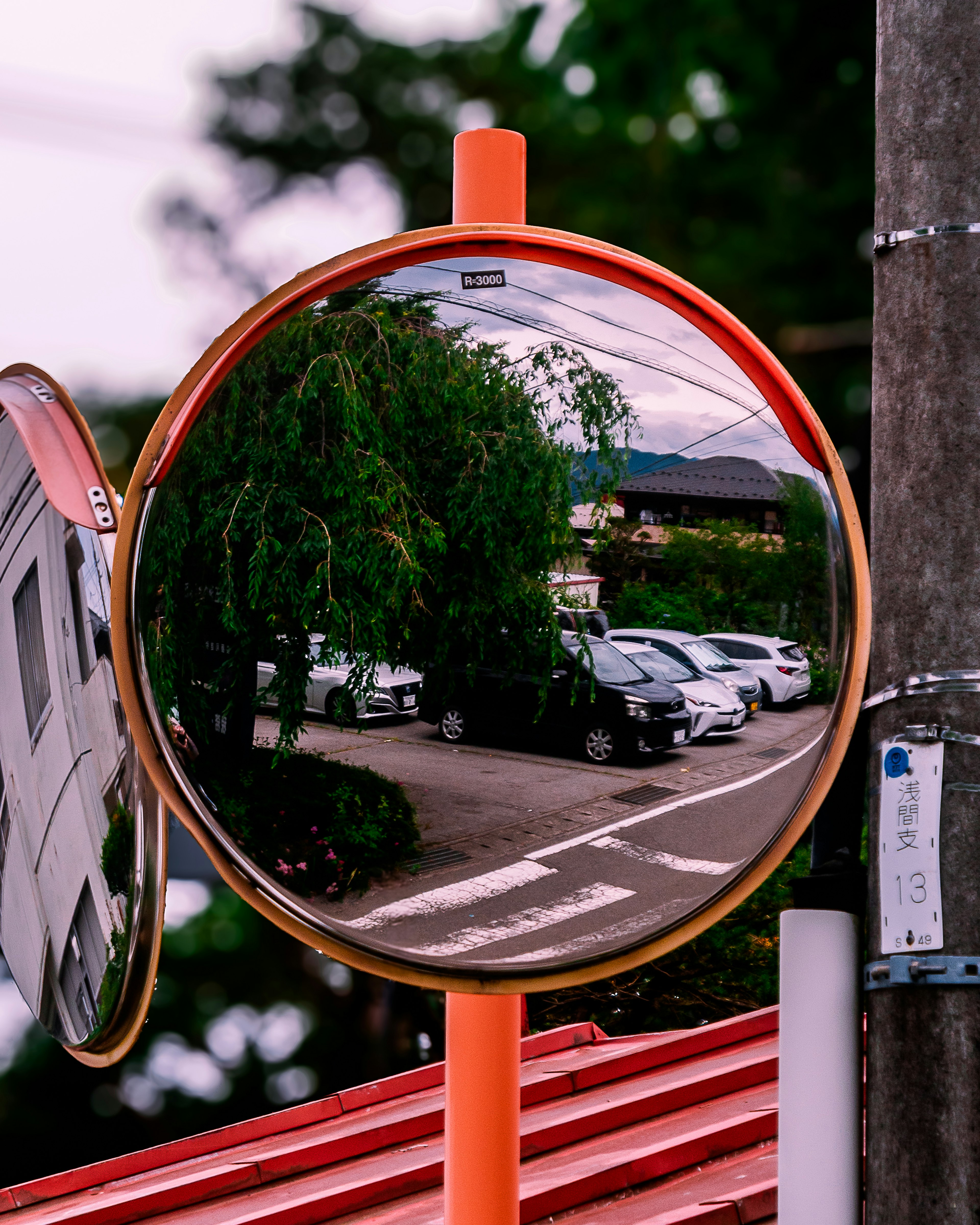 Traffic mirror reflecting a parking lot and surrounding scenery