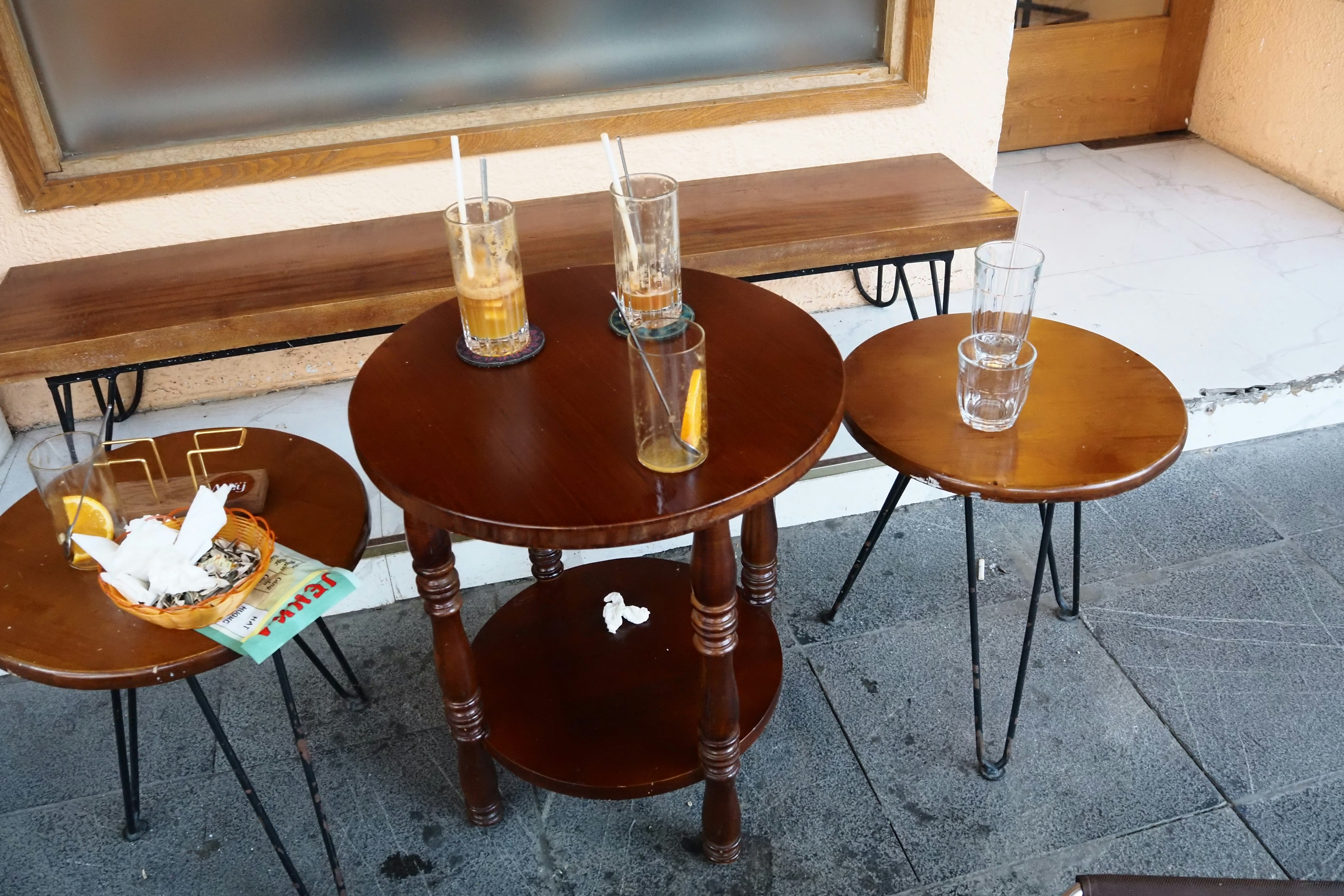 Table with drinks and scattered trash on a sidewalk