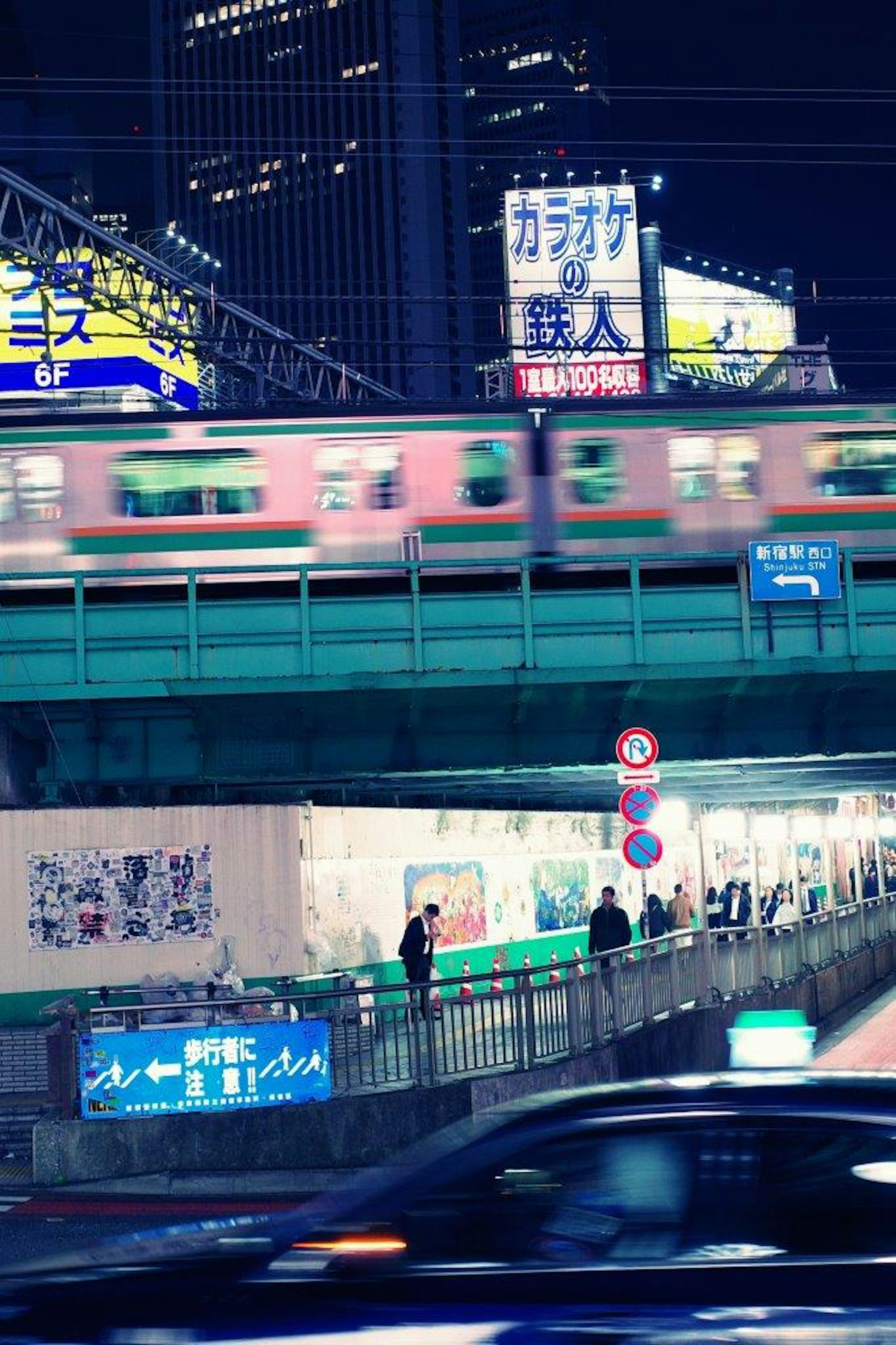 夜の街並みを走る電車とネオン看板が映る風景