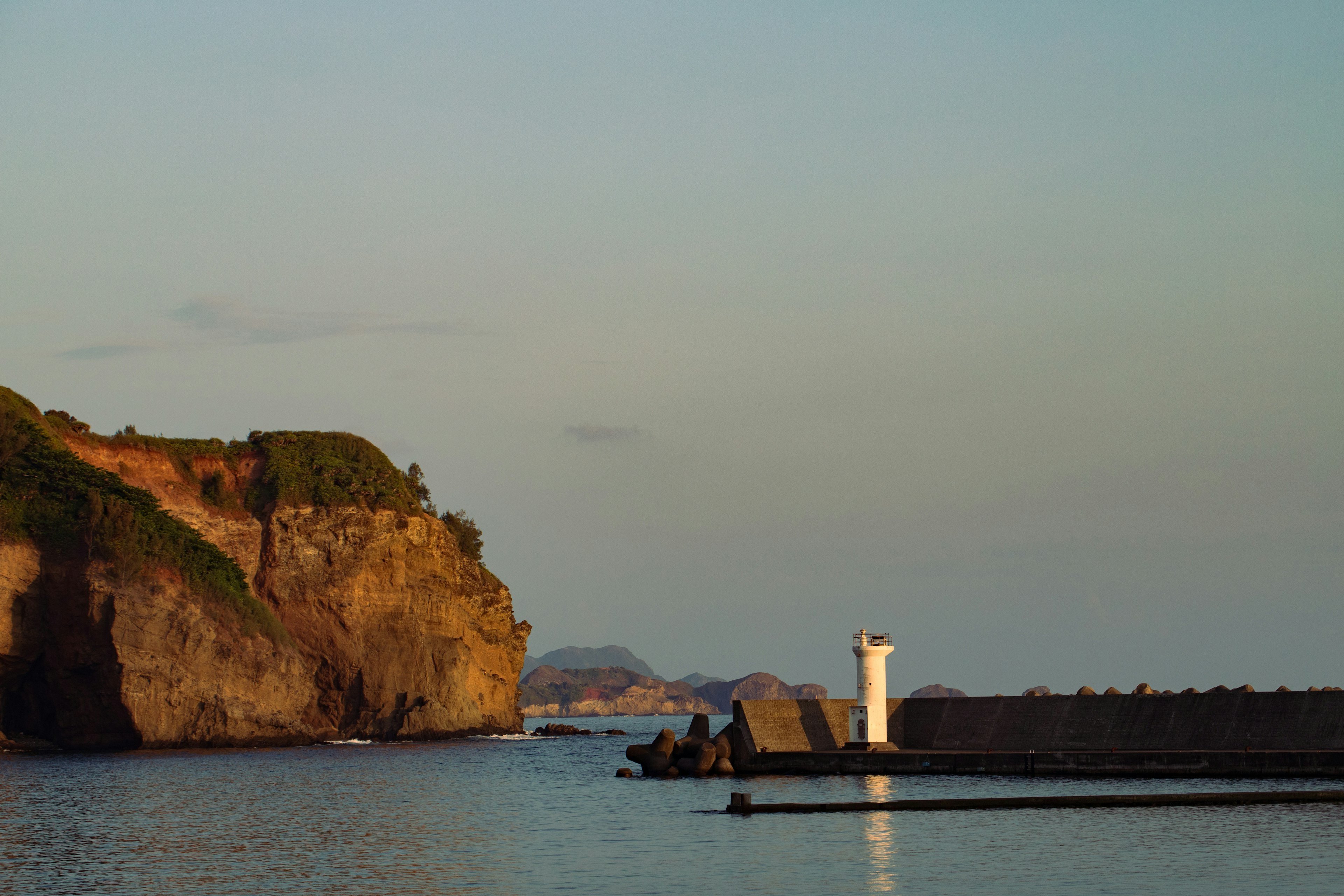 Escena costera con un faro y acantilados rocosos