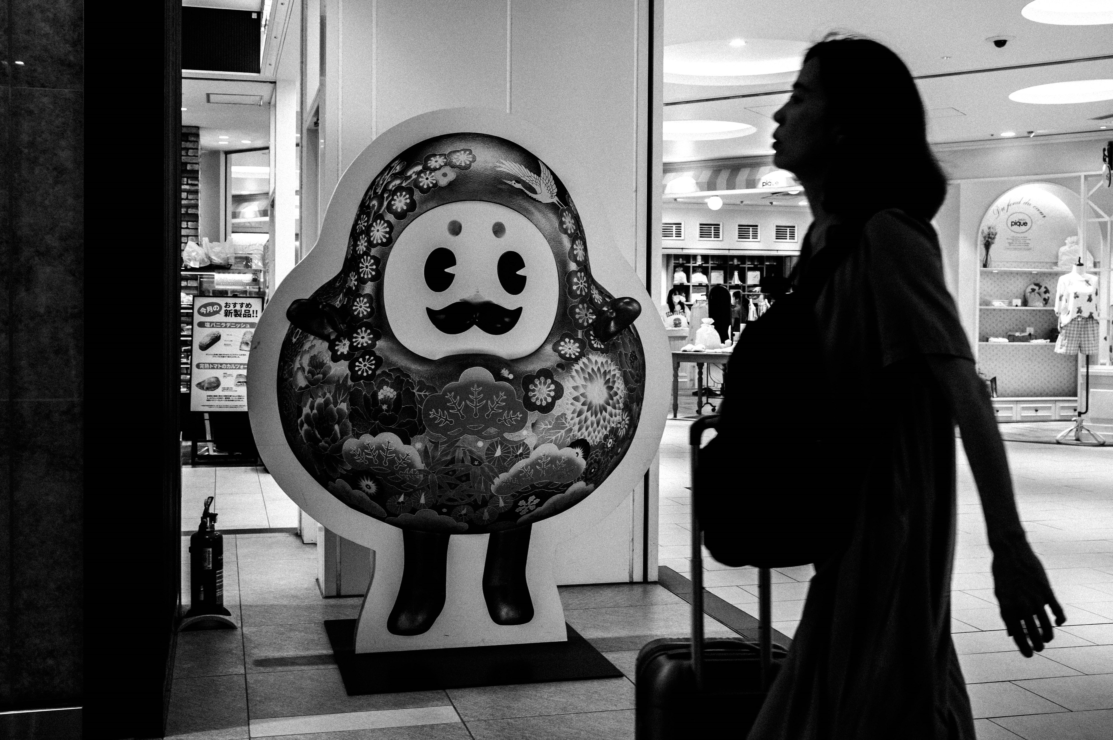 Silhouette of a woman with a suitcase walking beside a colorful character sign