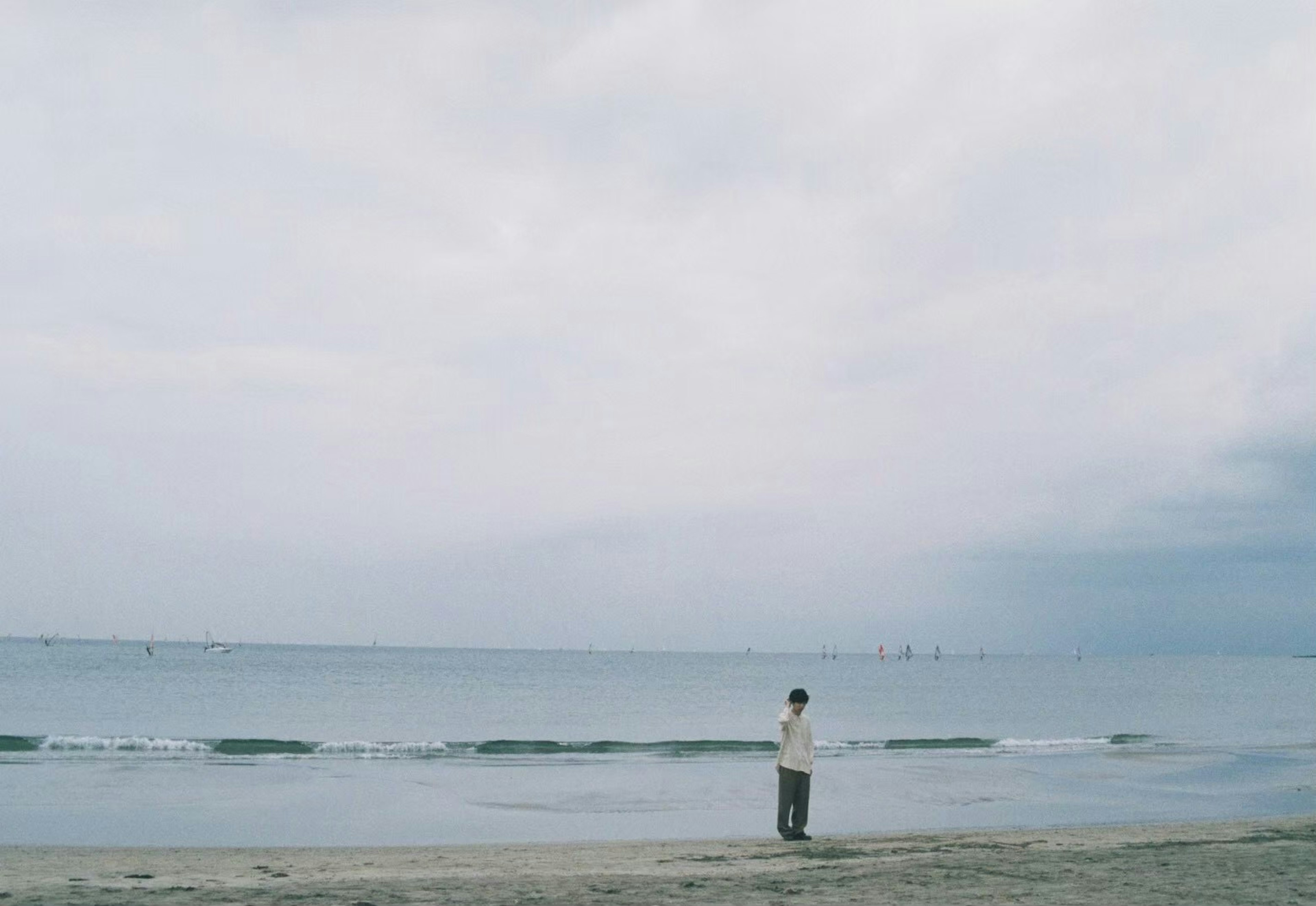 海辺で立つ人のシルエットと穏やかな波の景色