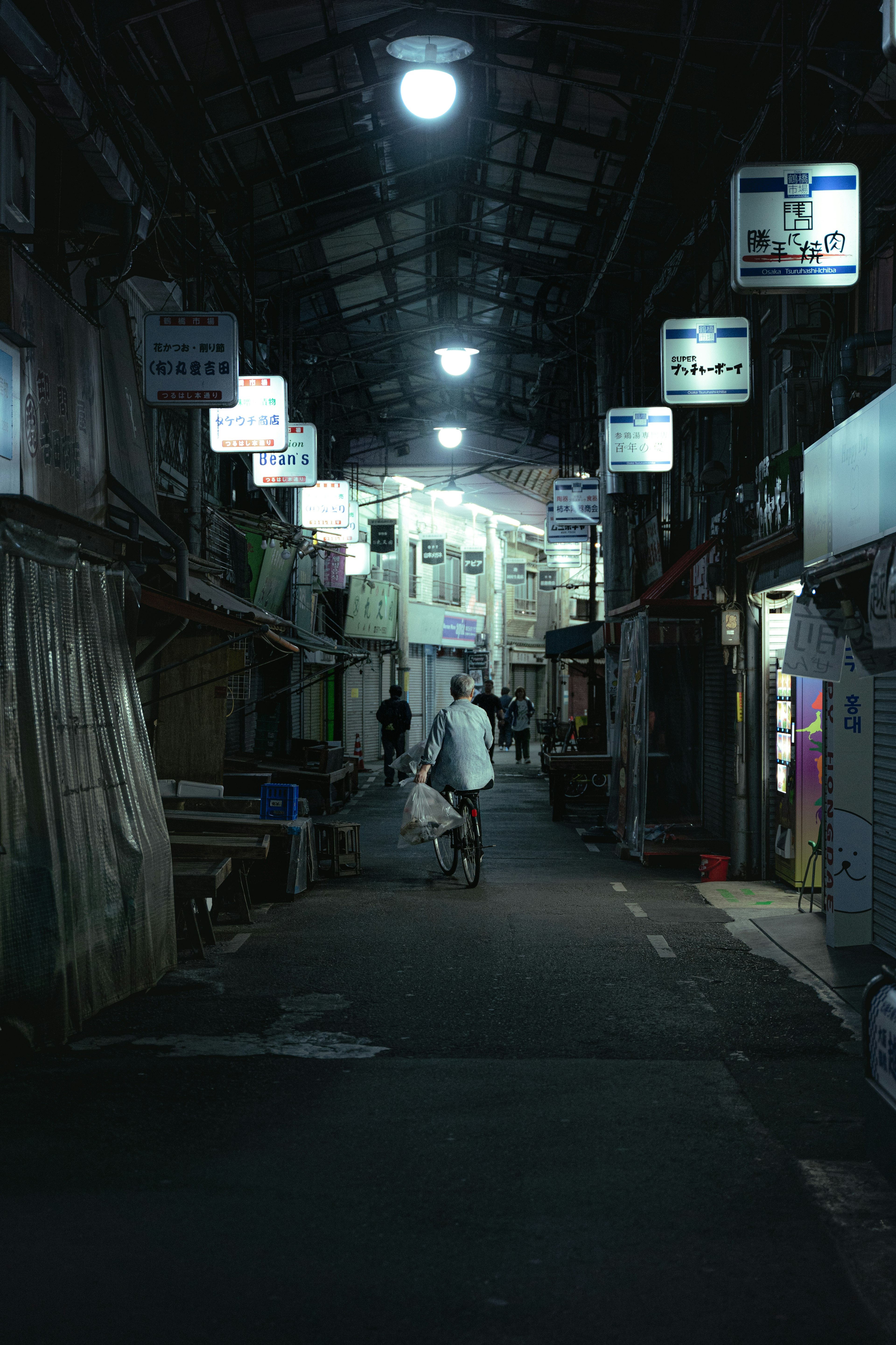 A person walking in a dimly lit alley lined with shops