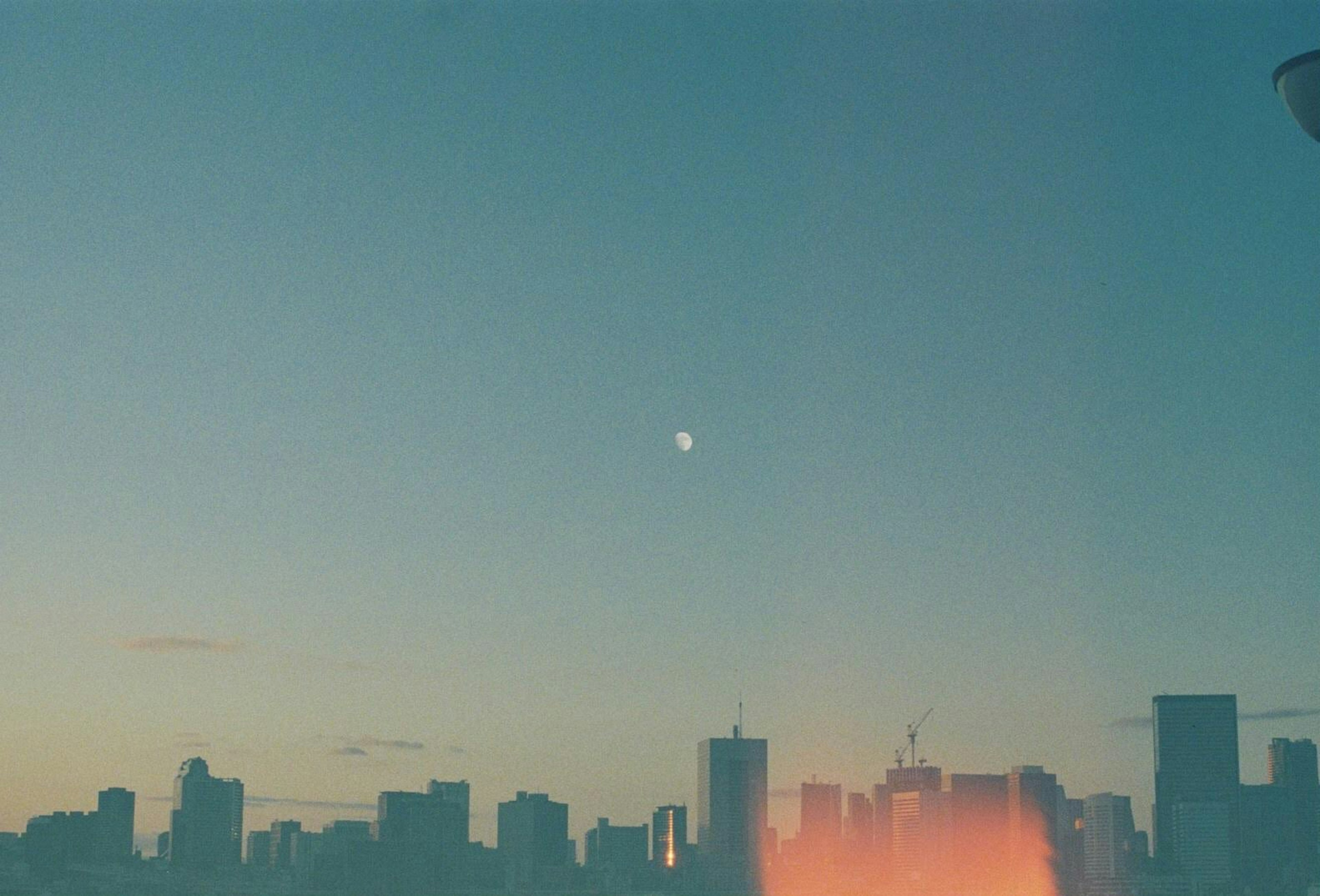 City skyline at dusk with a visible moon