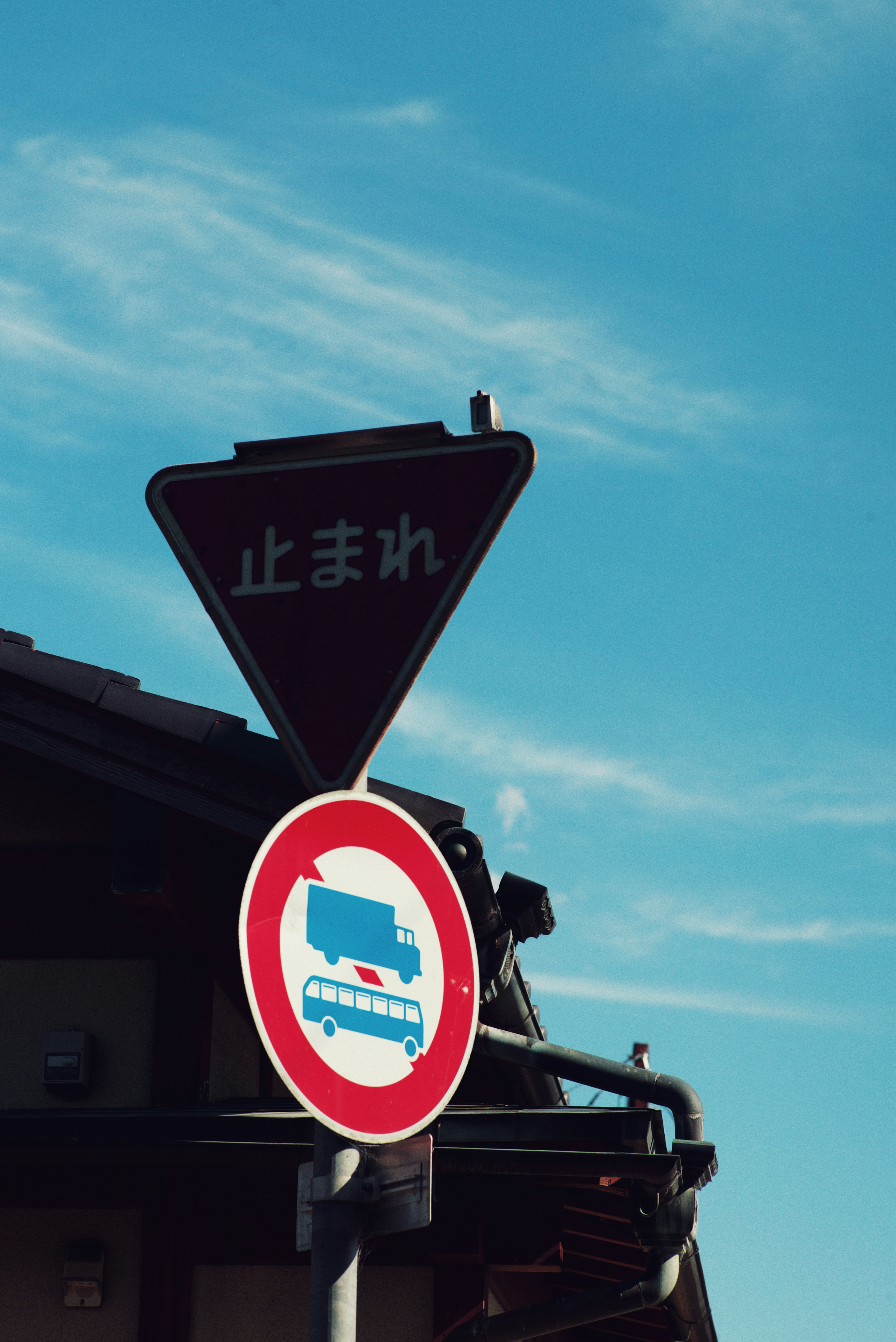 Traffic signs under a blue sky with Japanese text