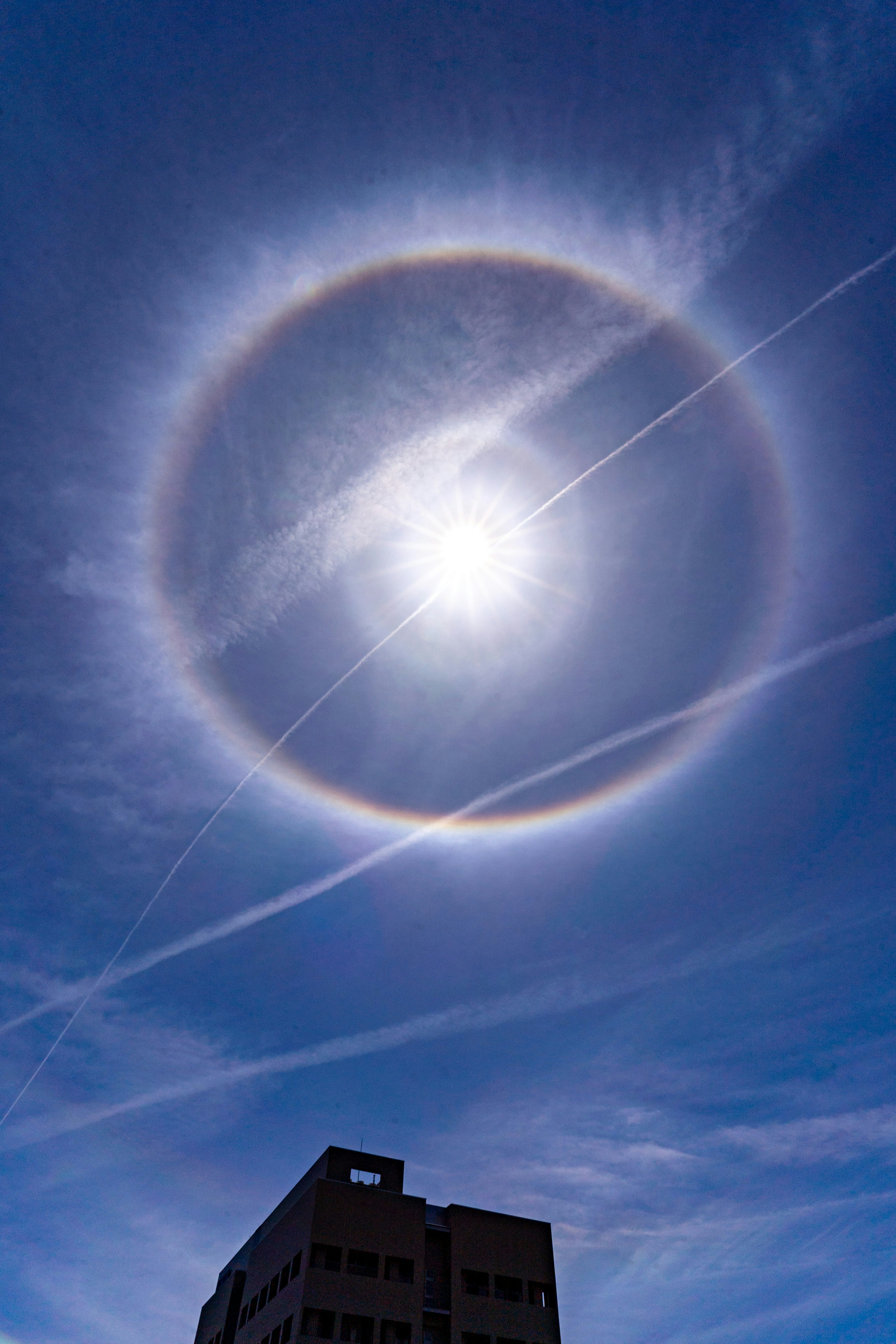 青空に大きな太陽の周りに虹のリングが見える