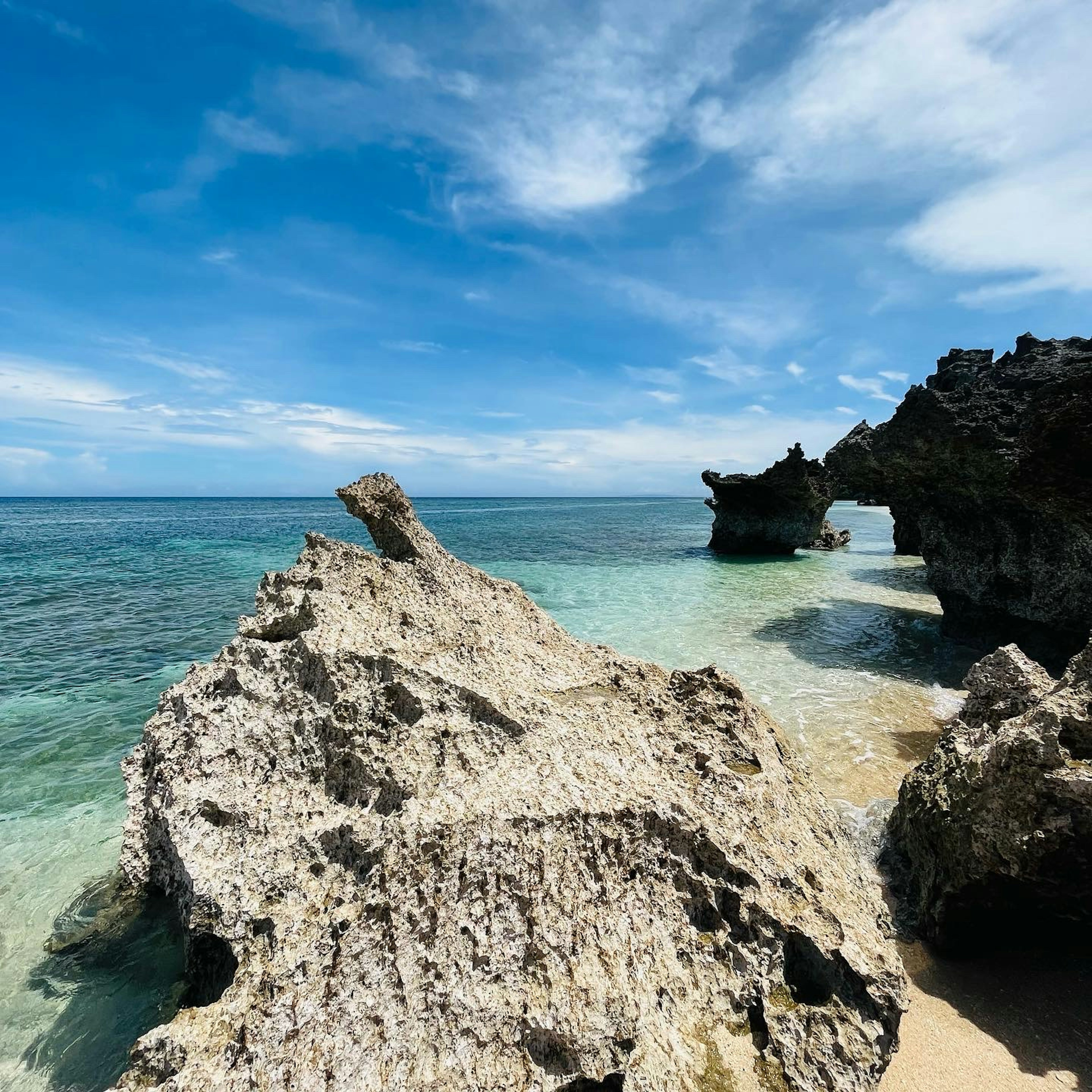 ทิวทัศน์ชายหาดที่มีทะเลสีน้ำเงินและรูปแบบหินที่เป็นเอกลักษณ์