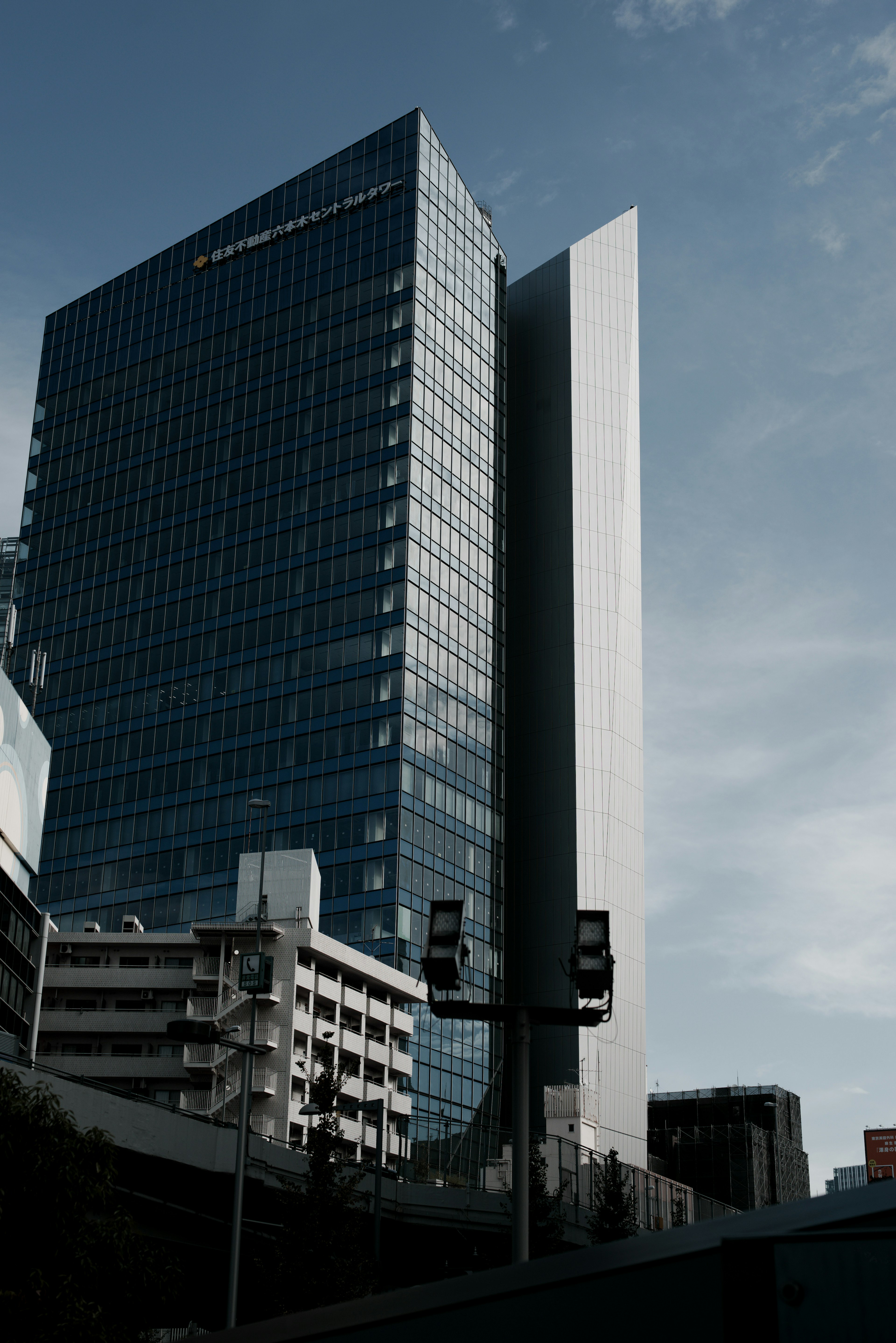 Moderne Hochhausfassade aus Glas unter blauem Himmel und Wolken