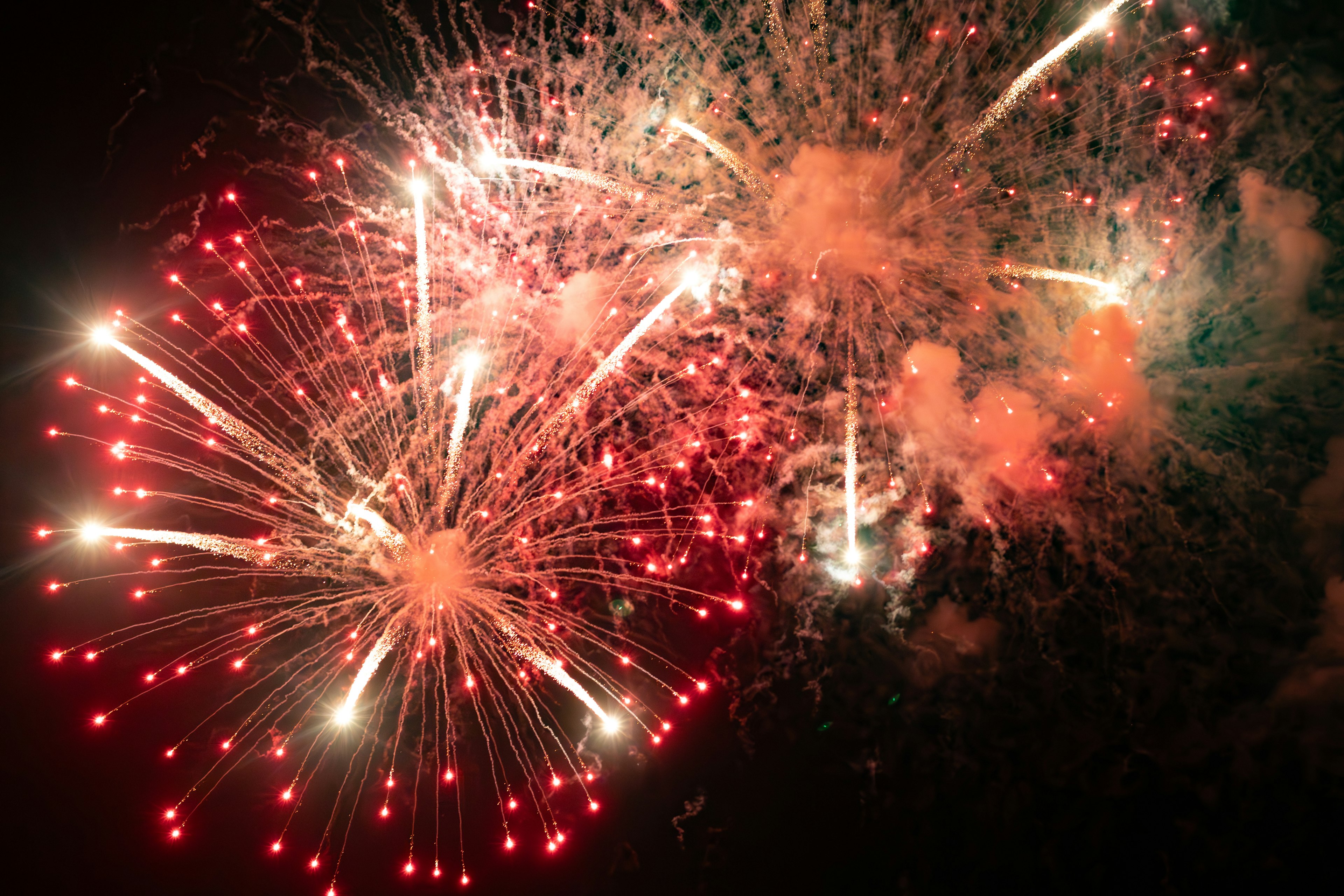 Brillantes fuegos artificiales rojos y blancos estallando en el cielo nocturno