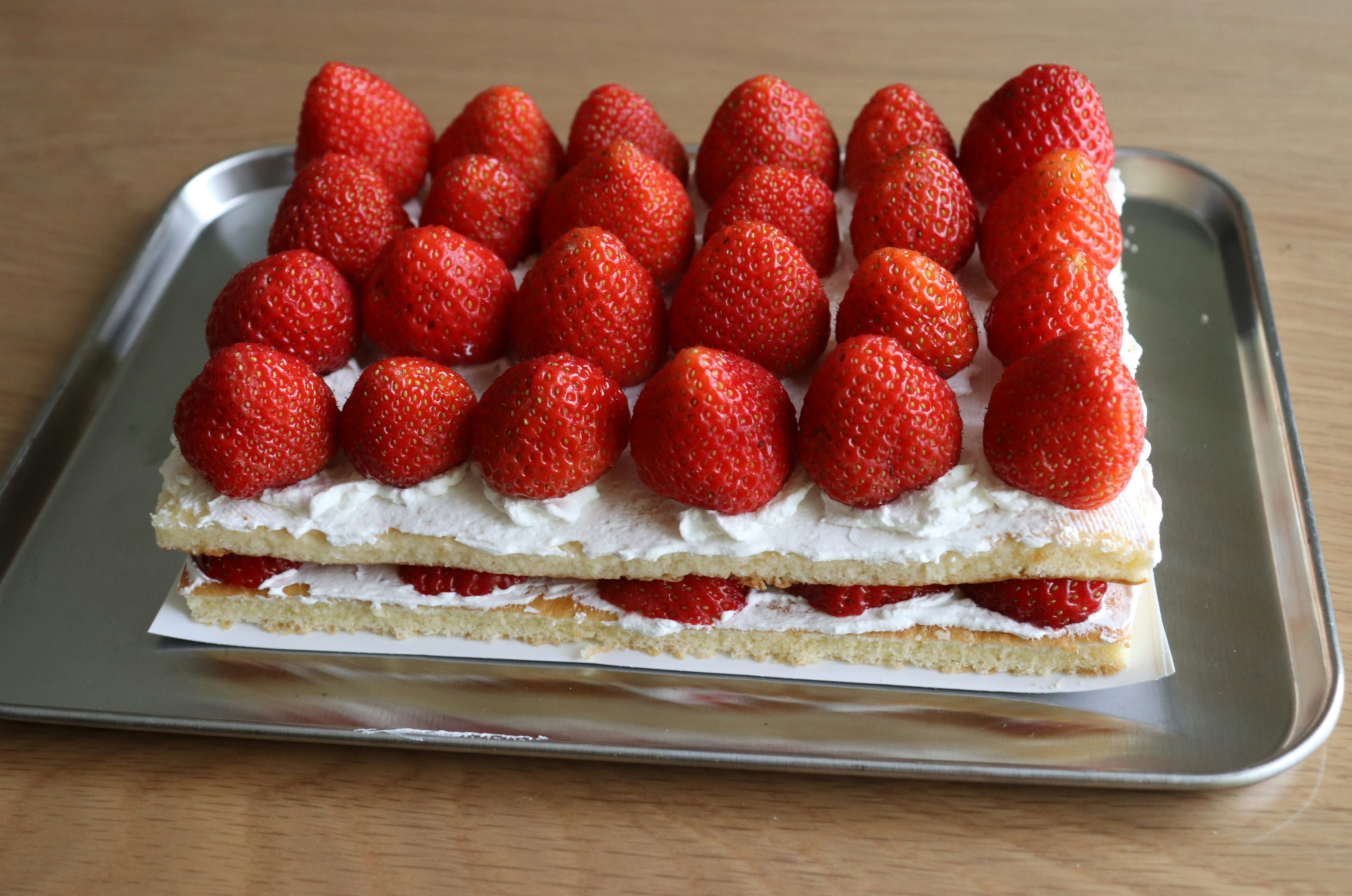 Strawberry topped layered cake on a silver tray