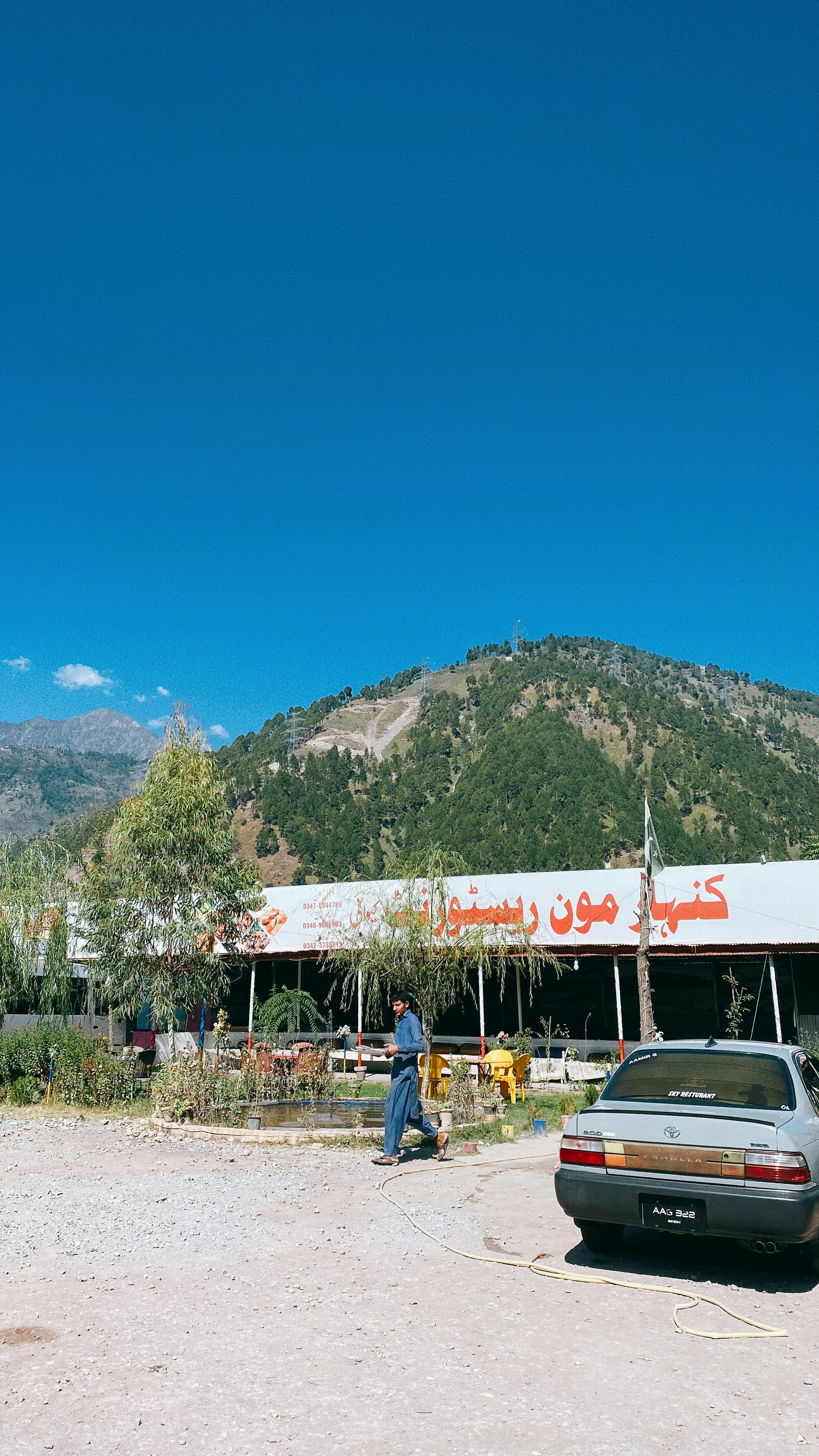 ภายนอกของร้านอาหารที่มีภูเขาอยู่เบื้องหลังใต้ท้องฟ้าสีฟ้าใส