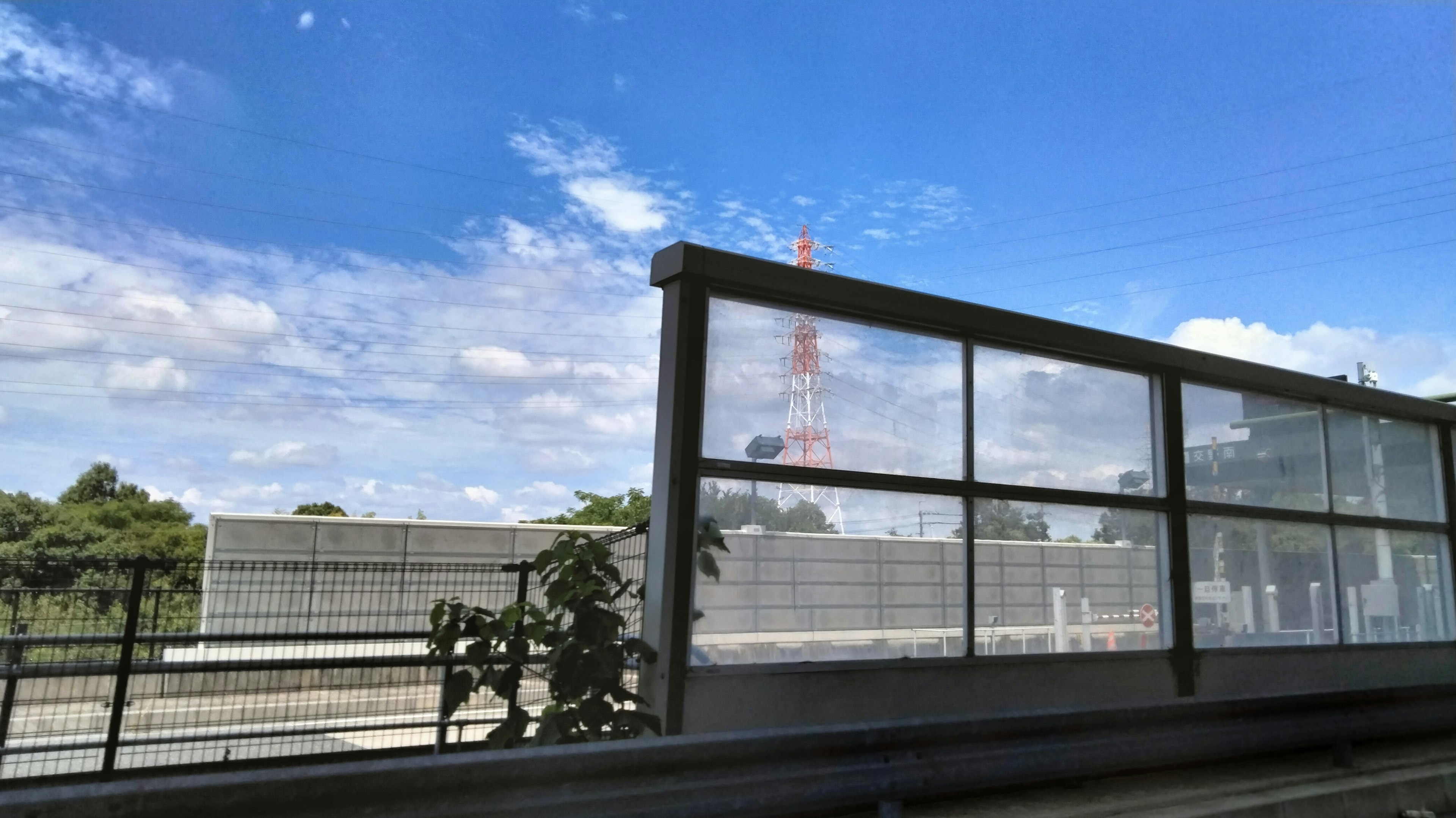 青空の下にあるガラスの壁と東京タワーが見える風景