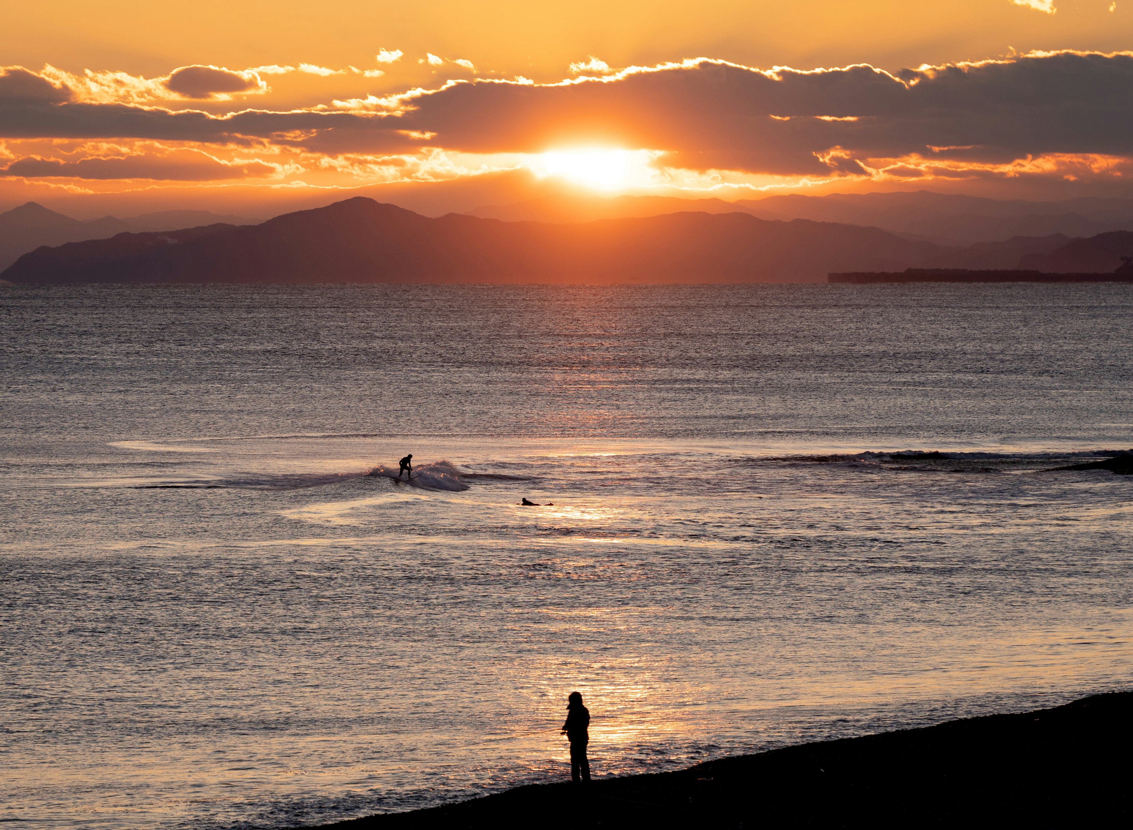 夕日が沈む海岸の風景とシルエットの人