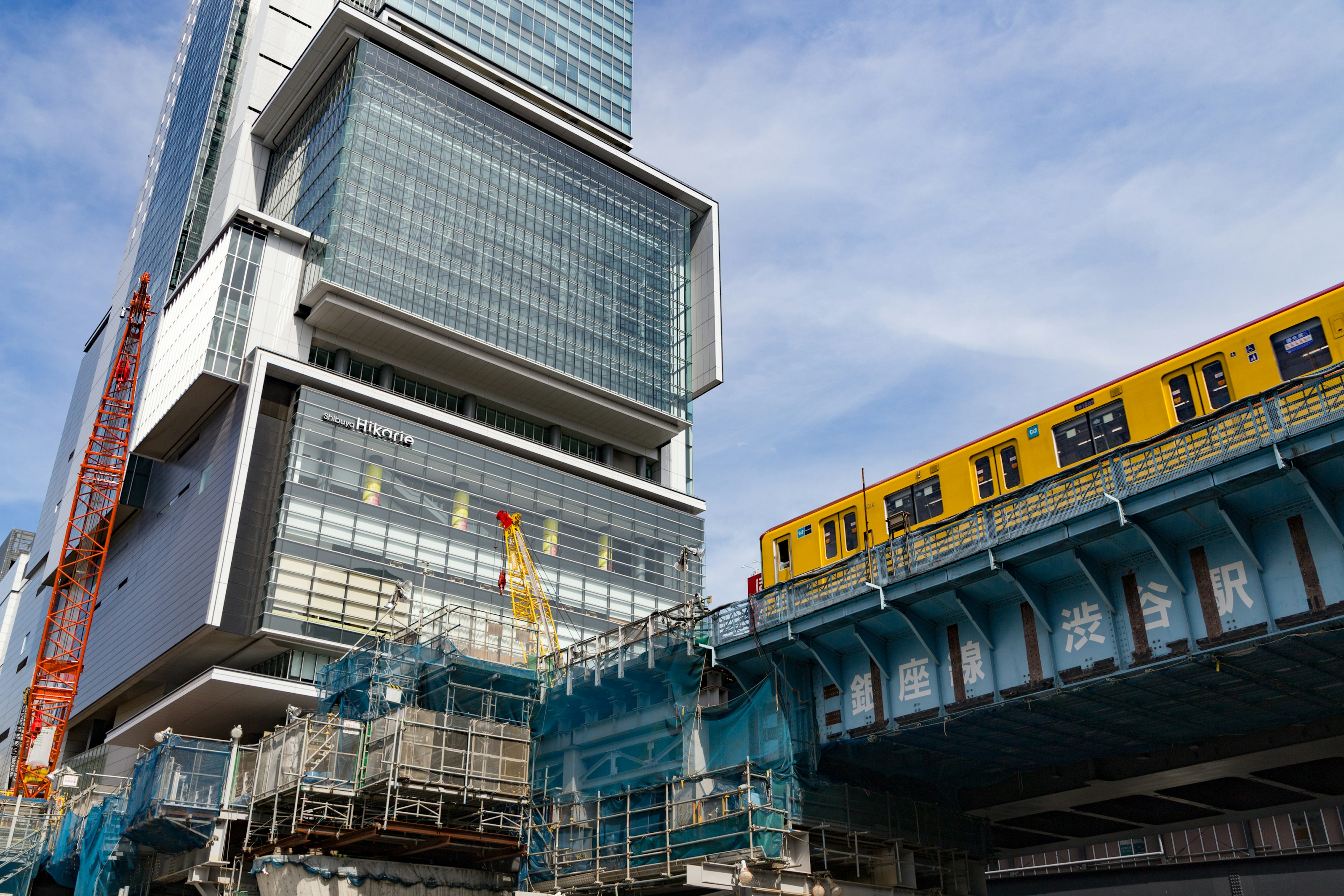 高層ビルと黄色い電車が交差する都市の風景