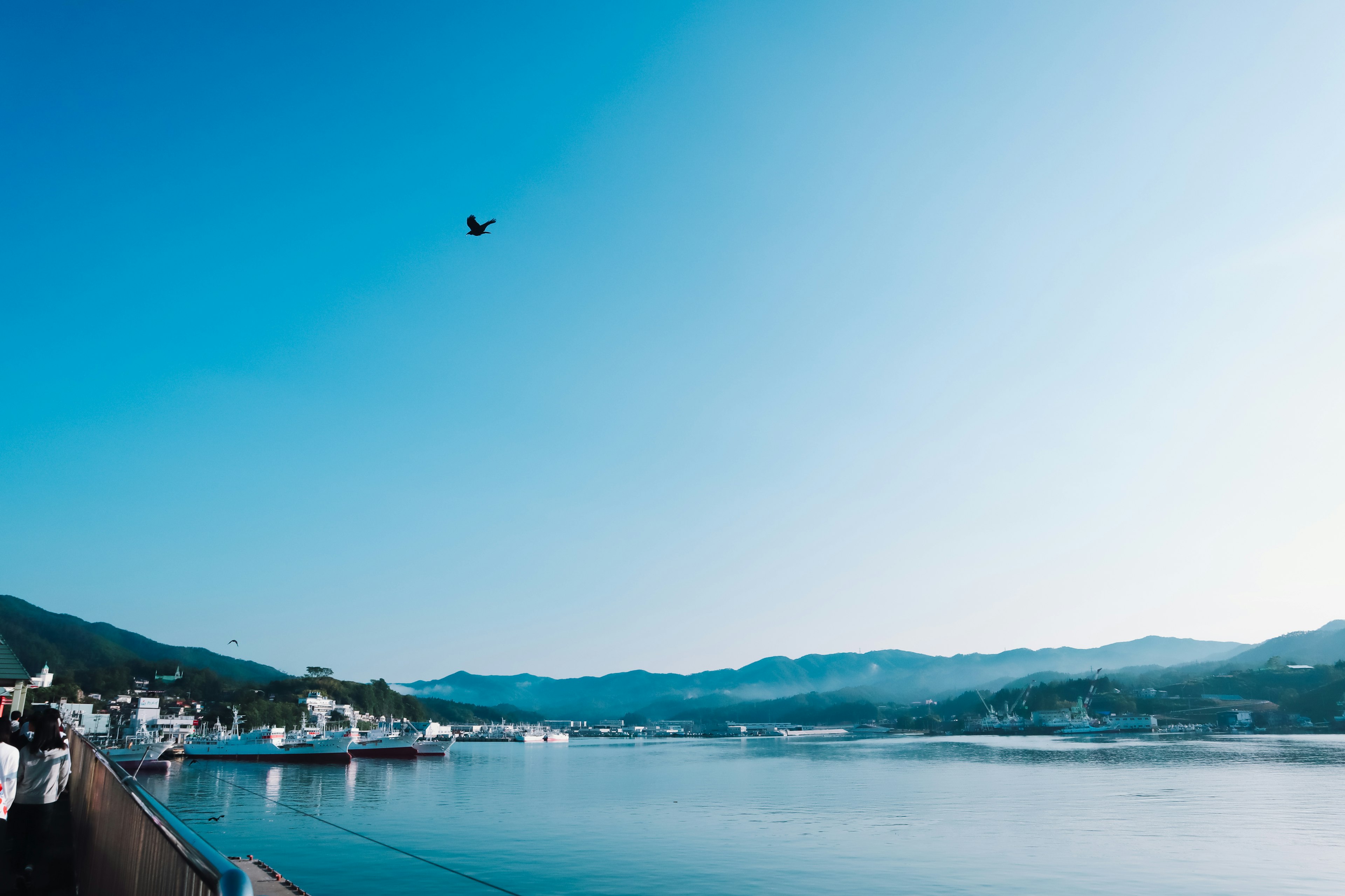 Scenic view featuring a blue sky and calm water with mountains and boats