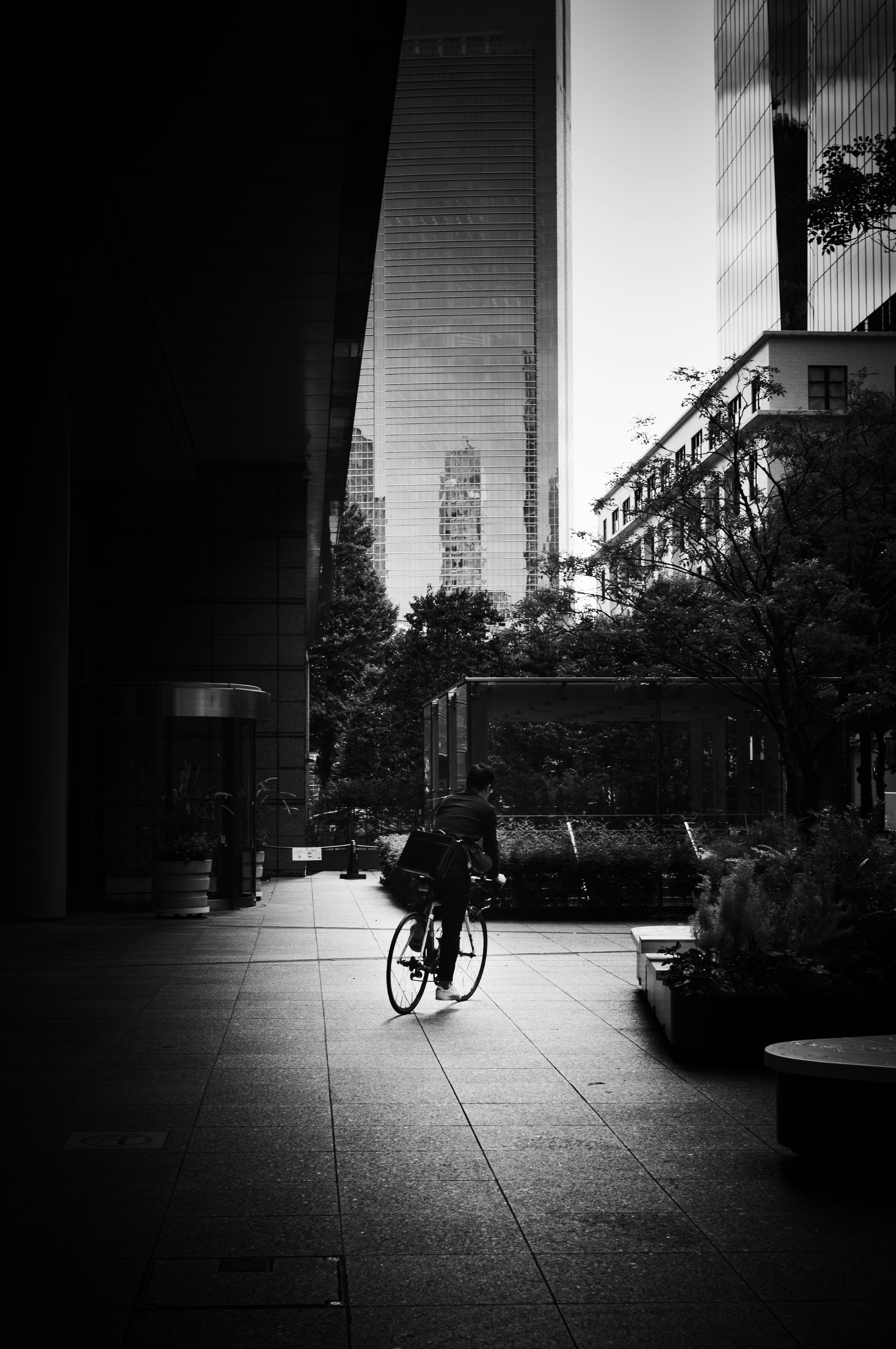 Scène urbaine en noir et blanc personne à vélo ombres de grands bâtiments