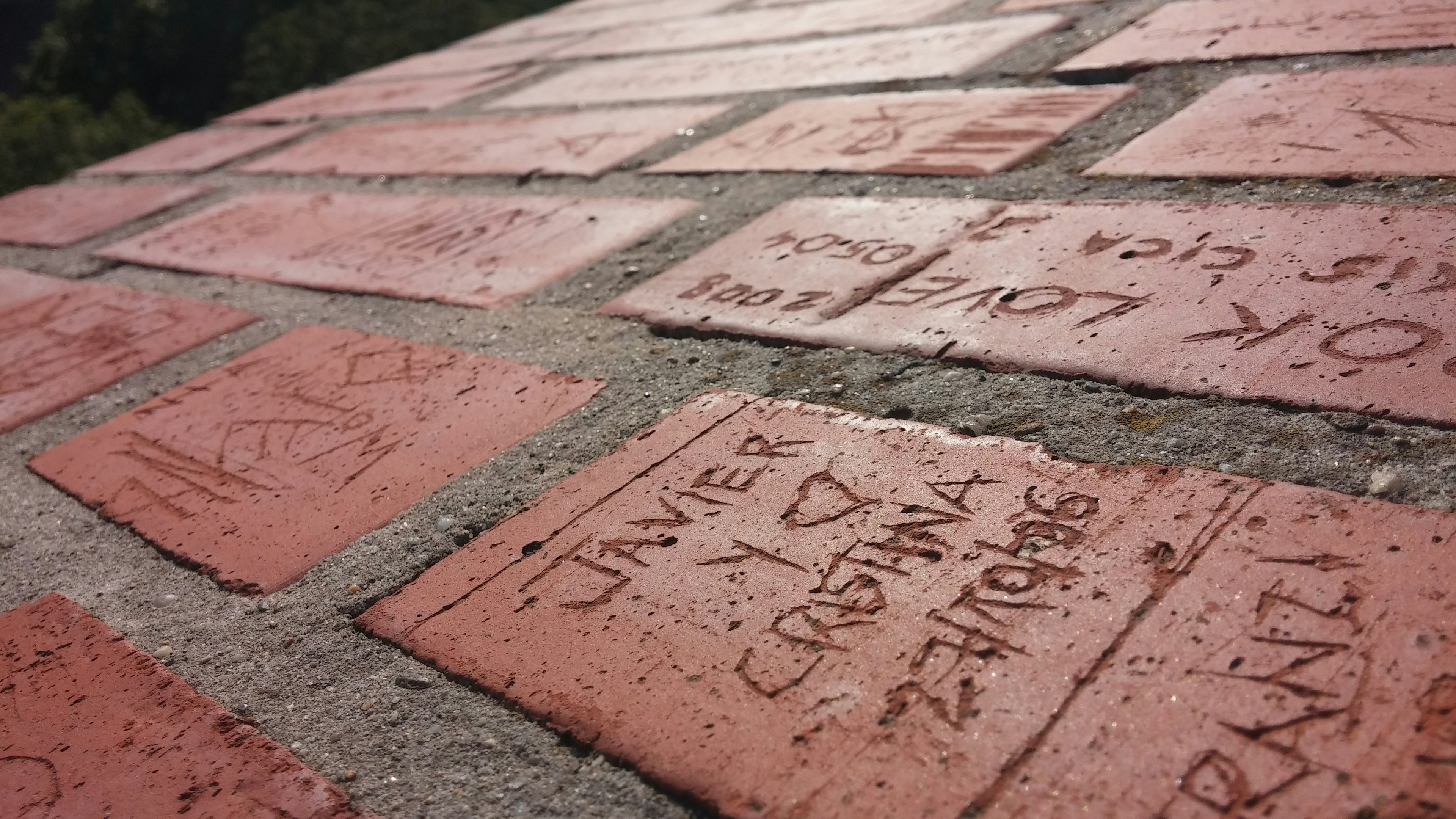 Messages et noms gravés sur des briques rouges