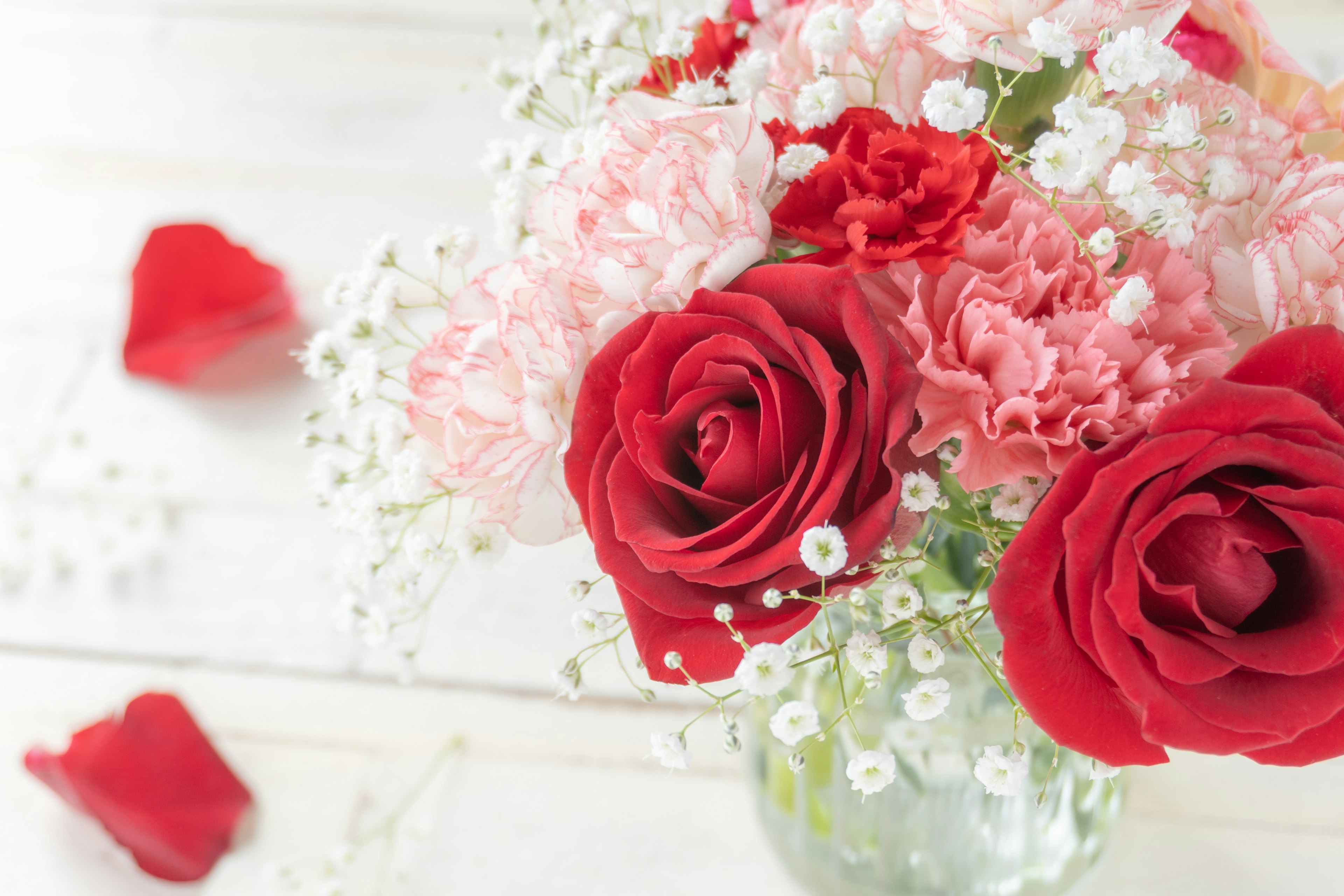 Ramo de rosas rojas y claveles con paniculata y pétalos de rosa roja